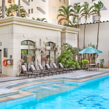a pool with chairs and umbrellas in front of a building