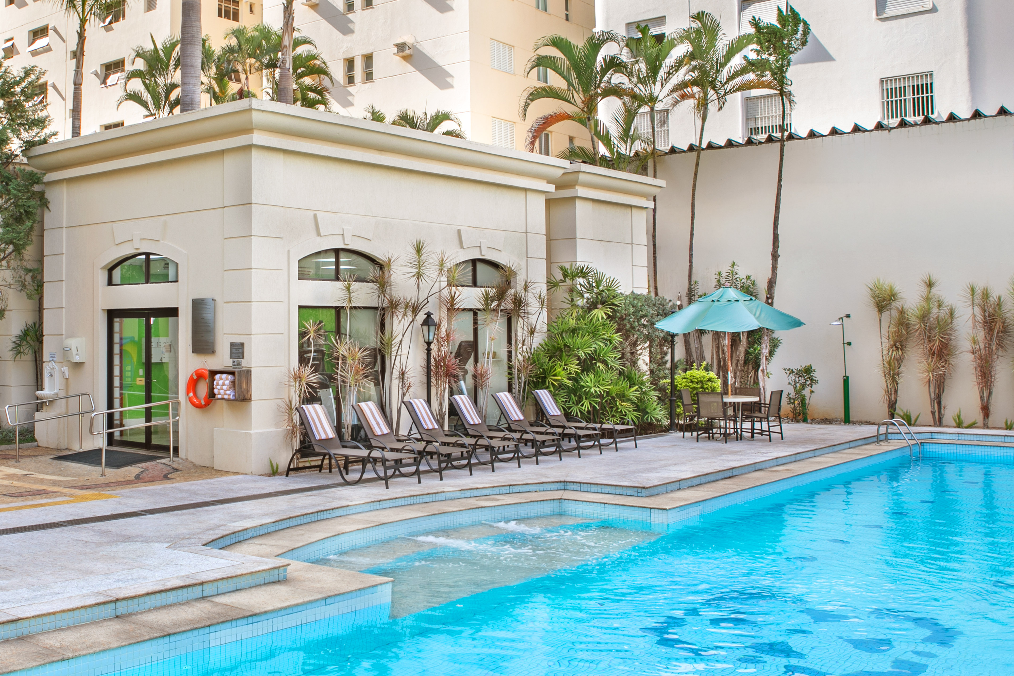 a pool with chairs and umbrellas in front of a building