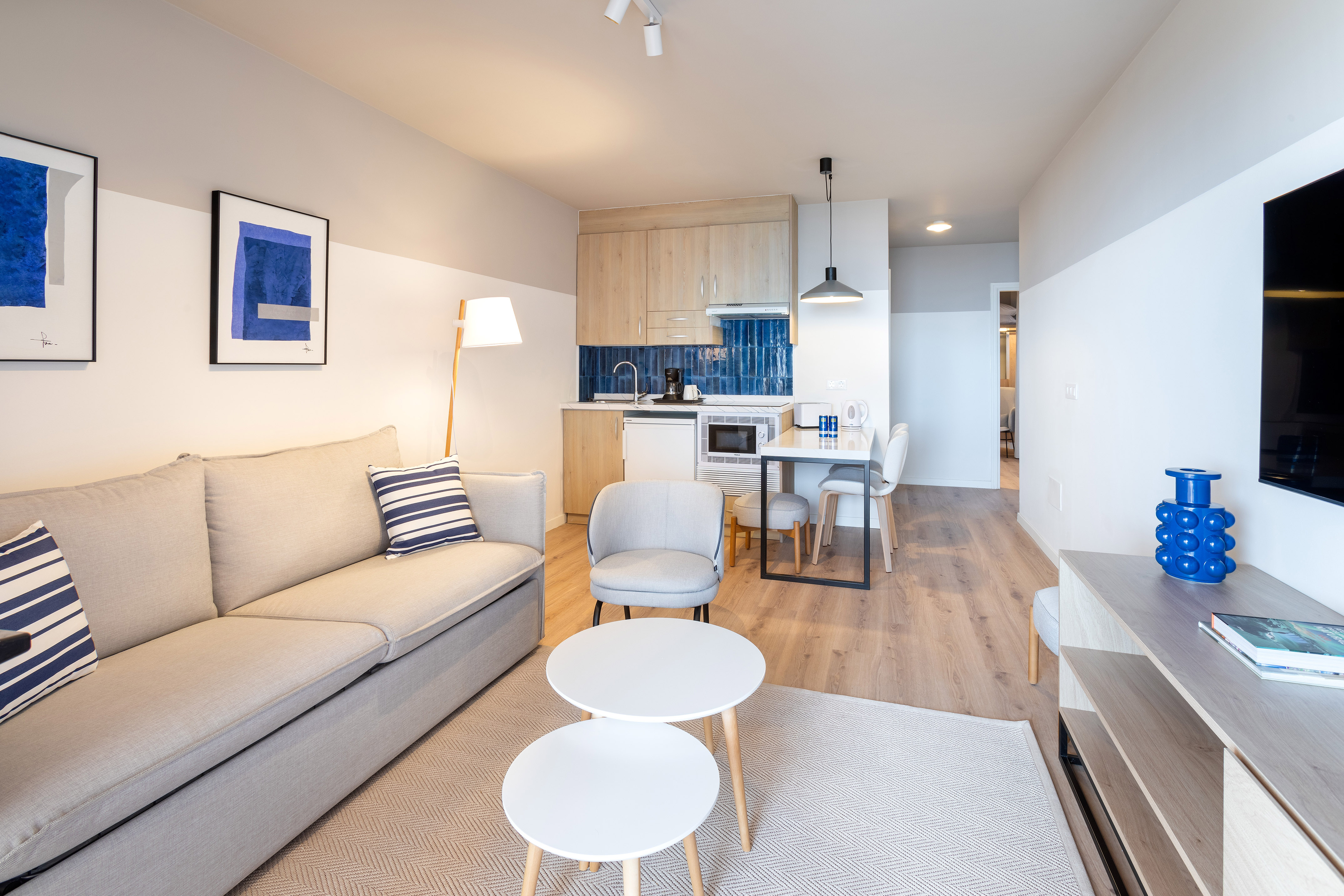 Cozy studio apartment featuring living area, kitchenette, dining. Modern, blue decor.