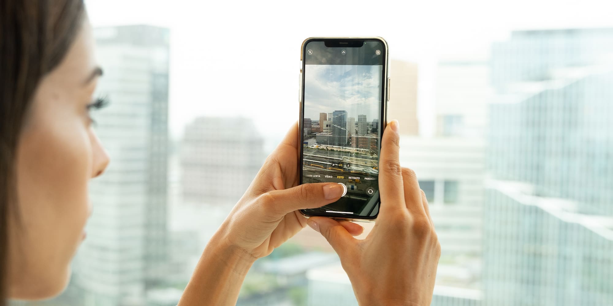 Person using smartphone camera to photograph urban city skyline.