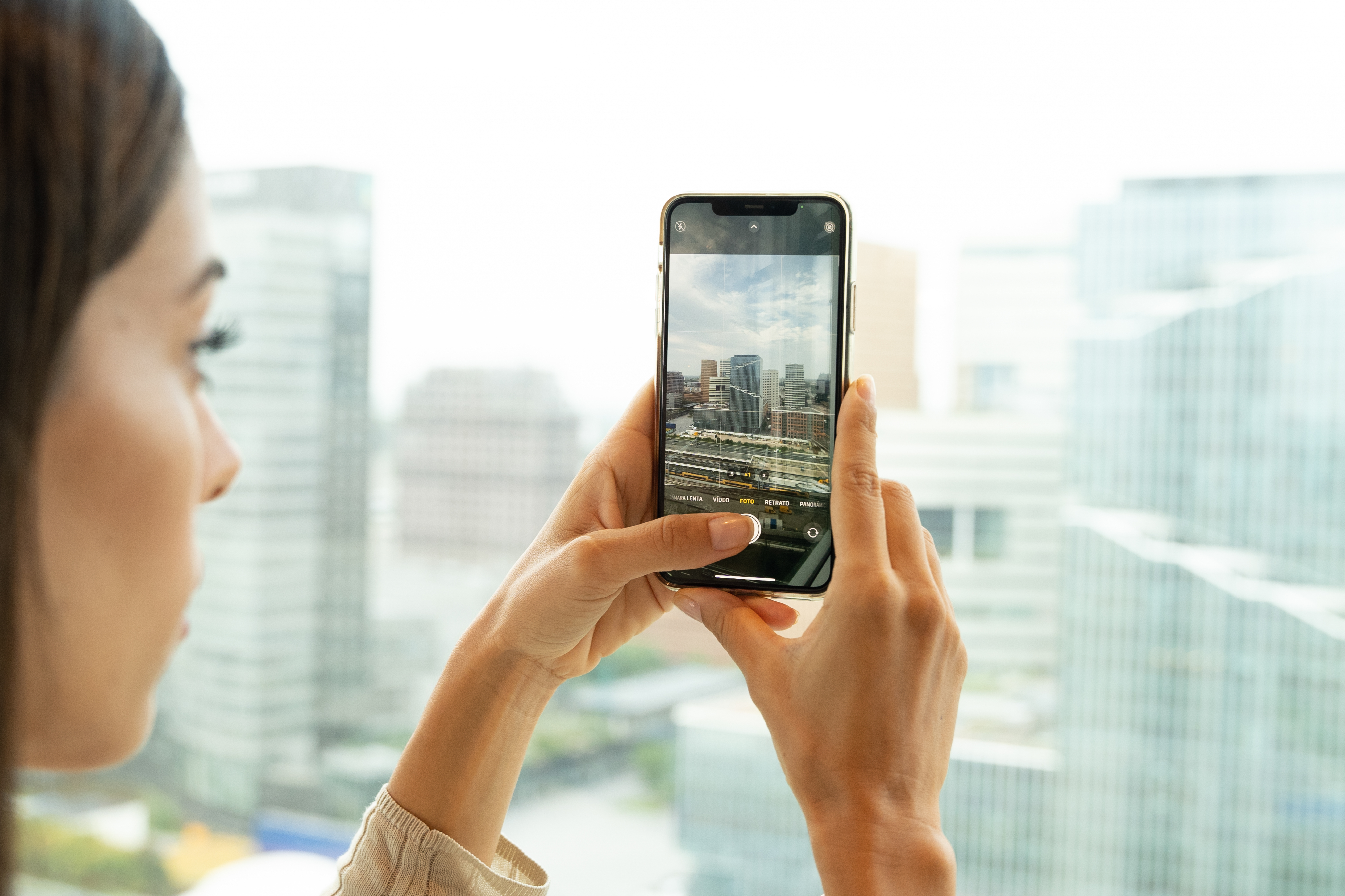 Person using smartphone camera to photograph urban city skyline.