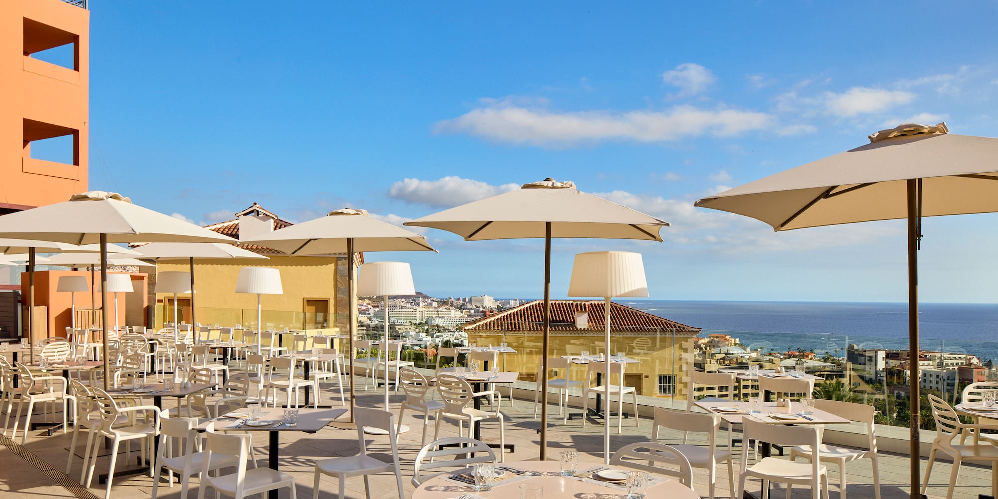 a group of tables and chairs with umbrellas on a rooftop