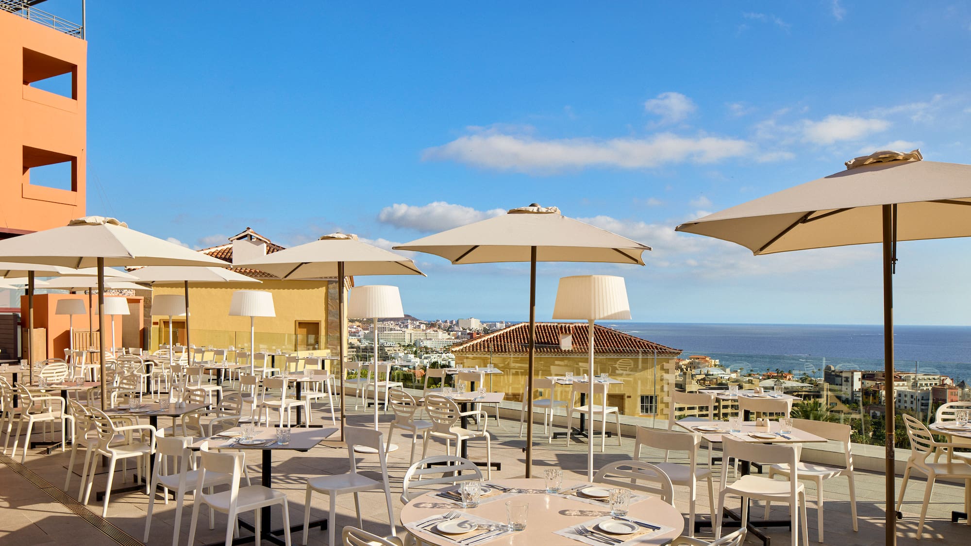 a group of tables and chairs with umbrellas on a rooftop