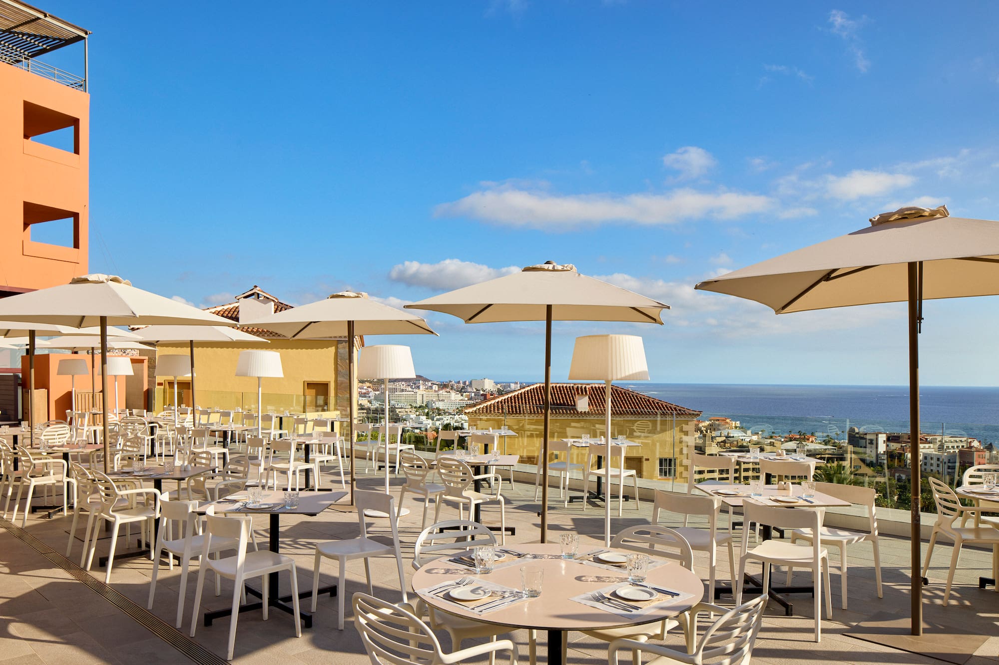 a group of tables and chairs with umbrellas on a rooftop