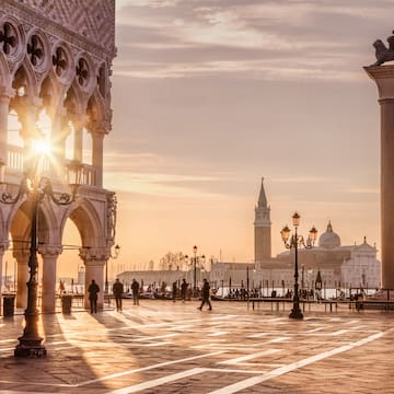 a large stone building with columns and a city in the background