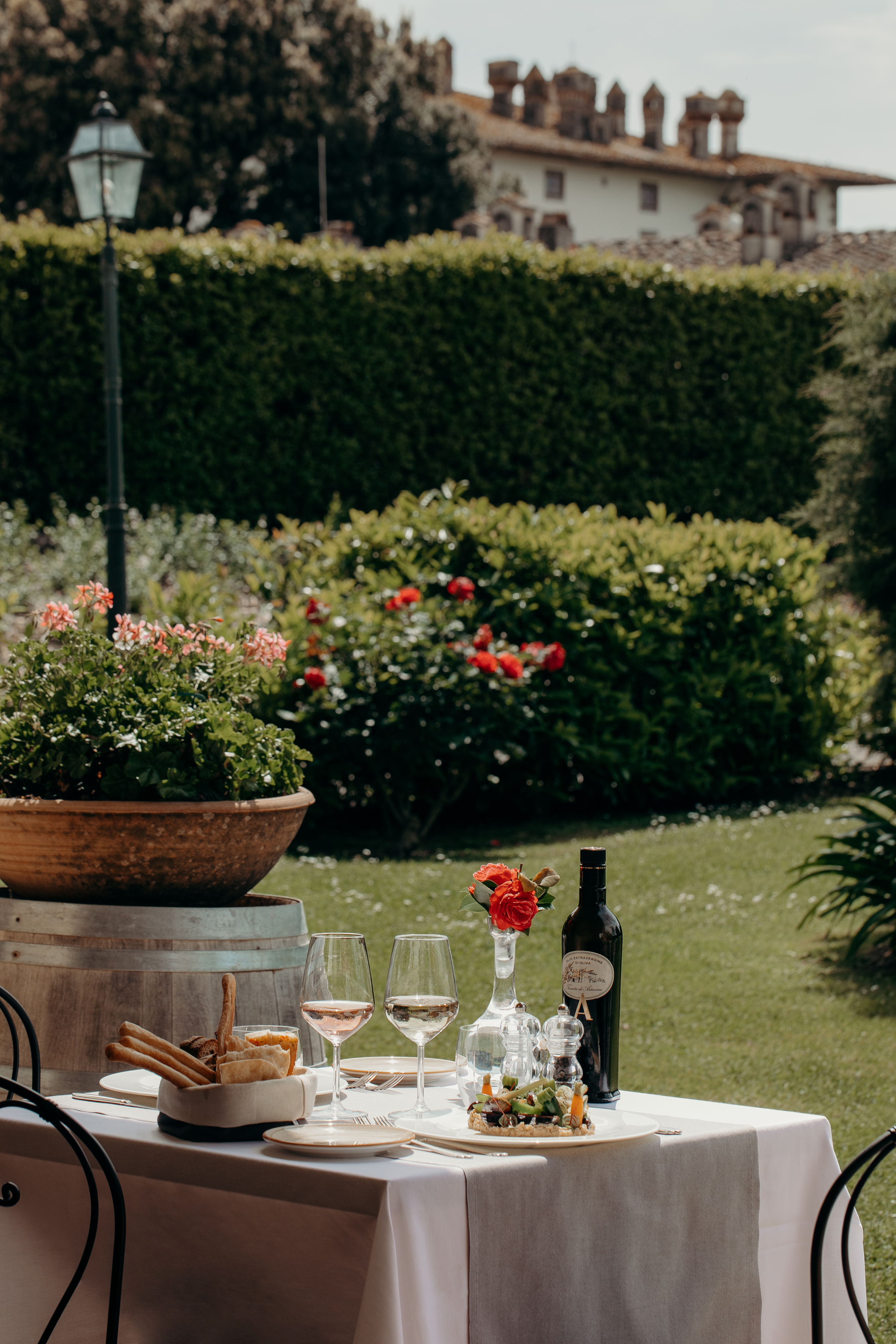 Al fresco dining table with wine, appetizer, olive oil in an Italian garden.