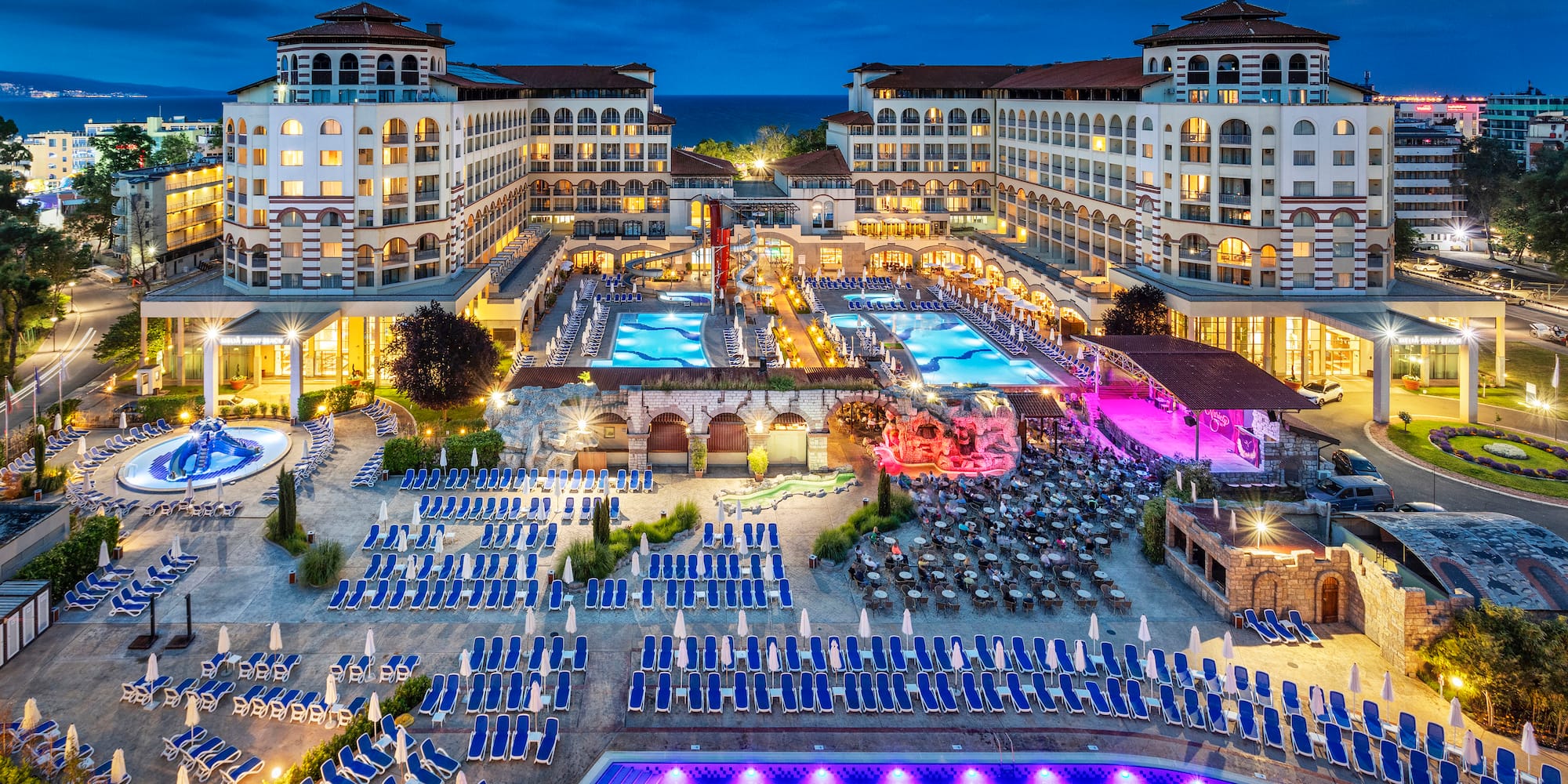 a pool and hotel with many chairs