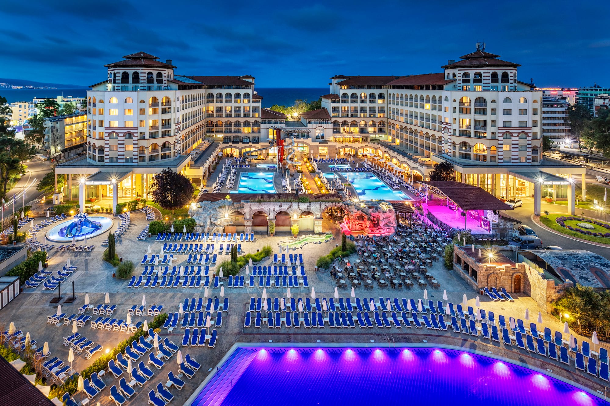a pool and hotel with many chairs