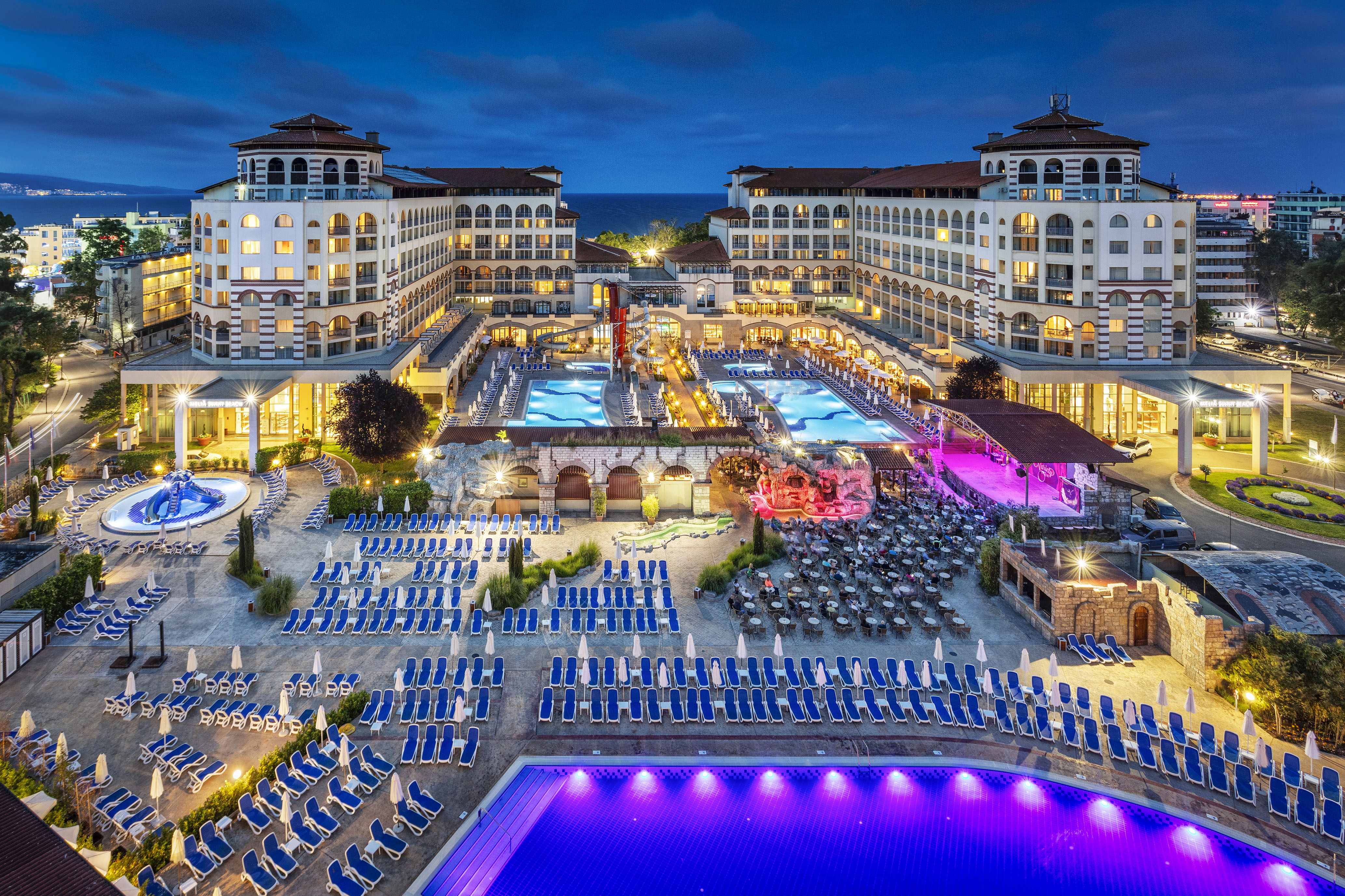 a pool and hotel with many chairs