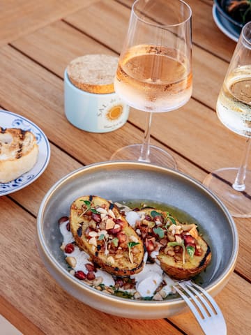 food in a bowl next to two glasses of champagne