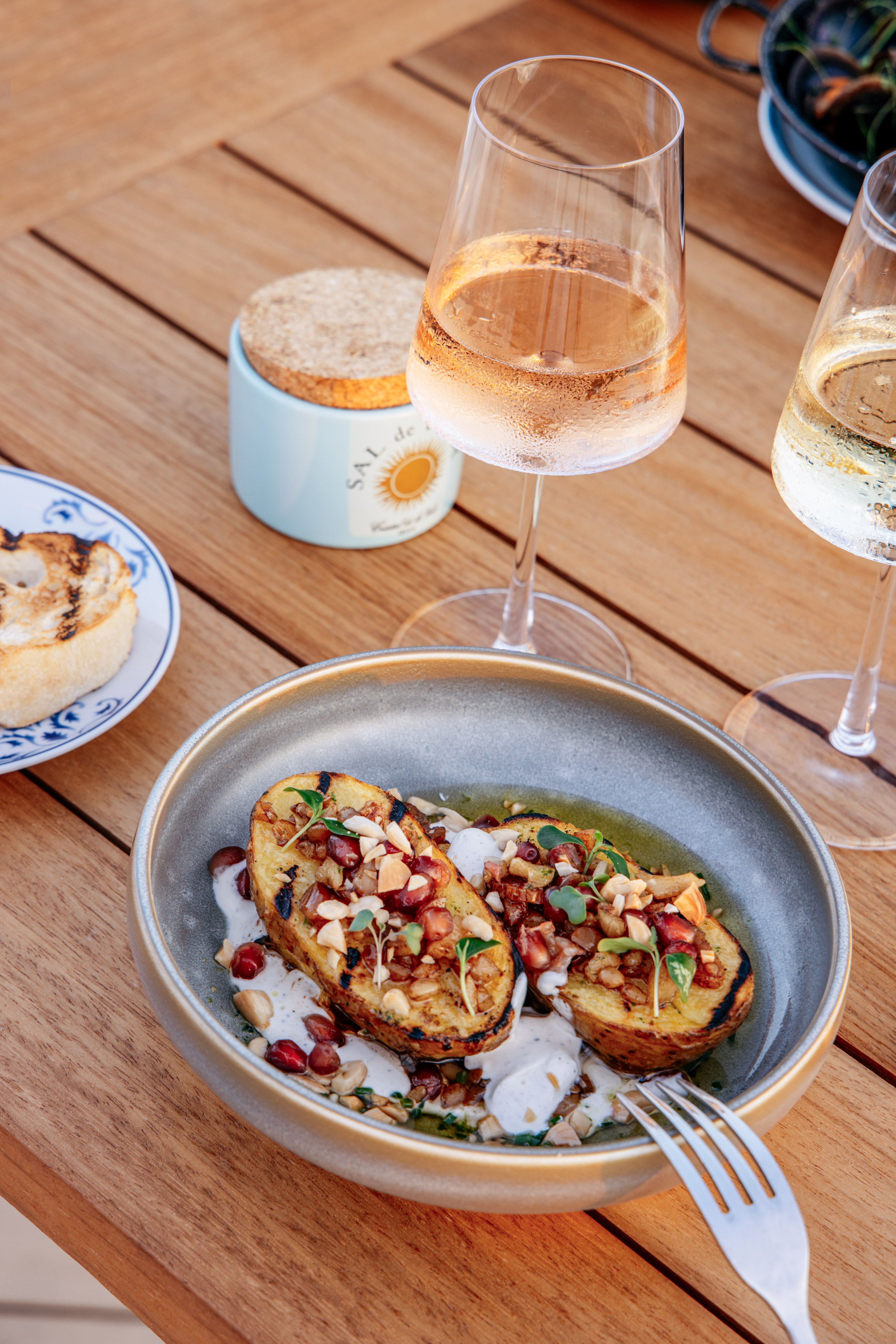 Grilled potato halves with pomegranate, nuts, microgreens, and rosé wine.
