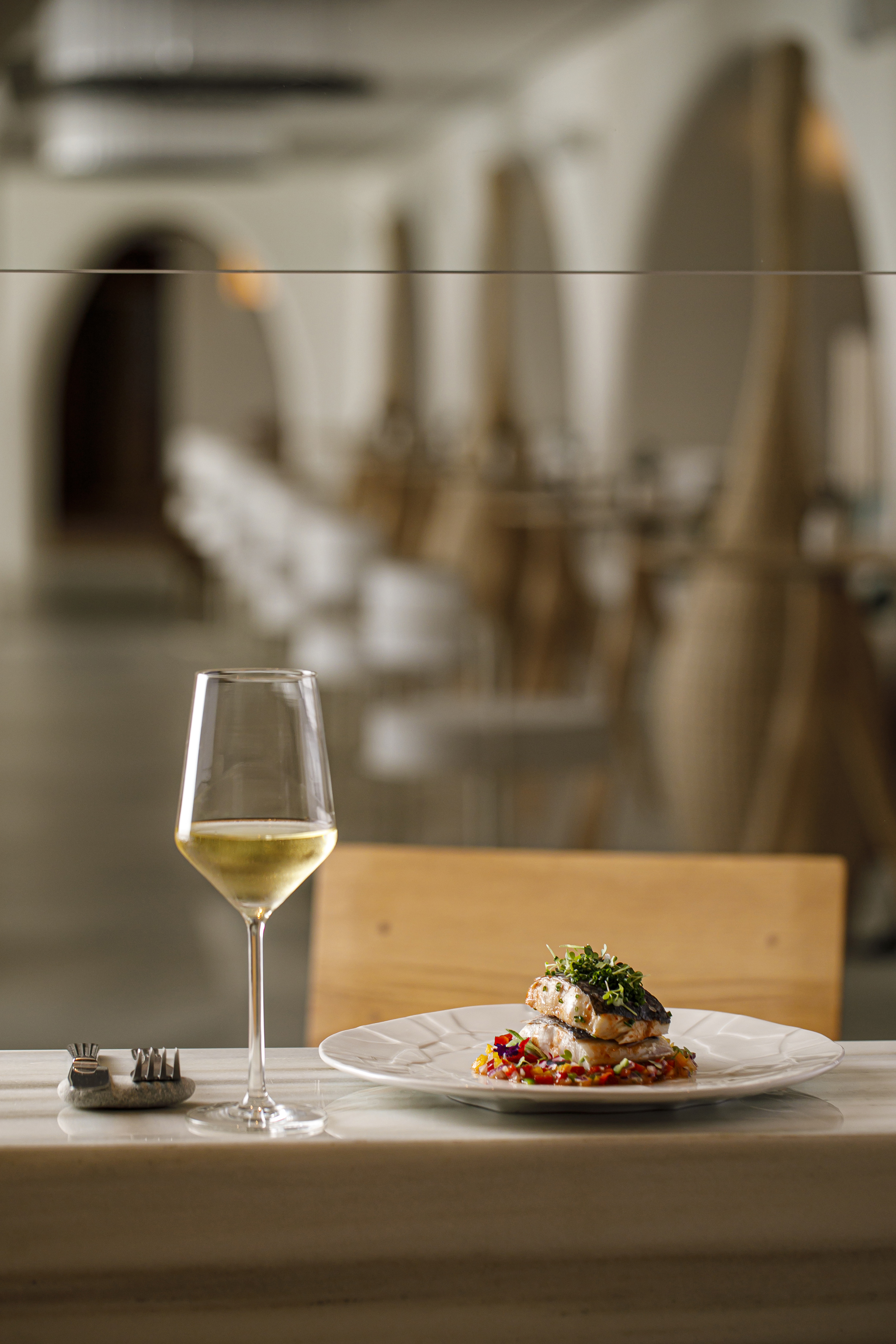 Gourmet fish dish with white wine on marble table, modern restaurant.