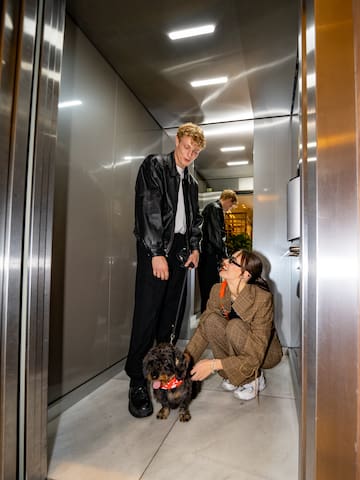 a man and woman in an elevator with a dog