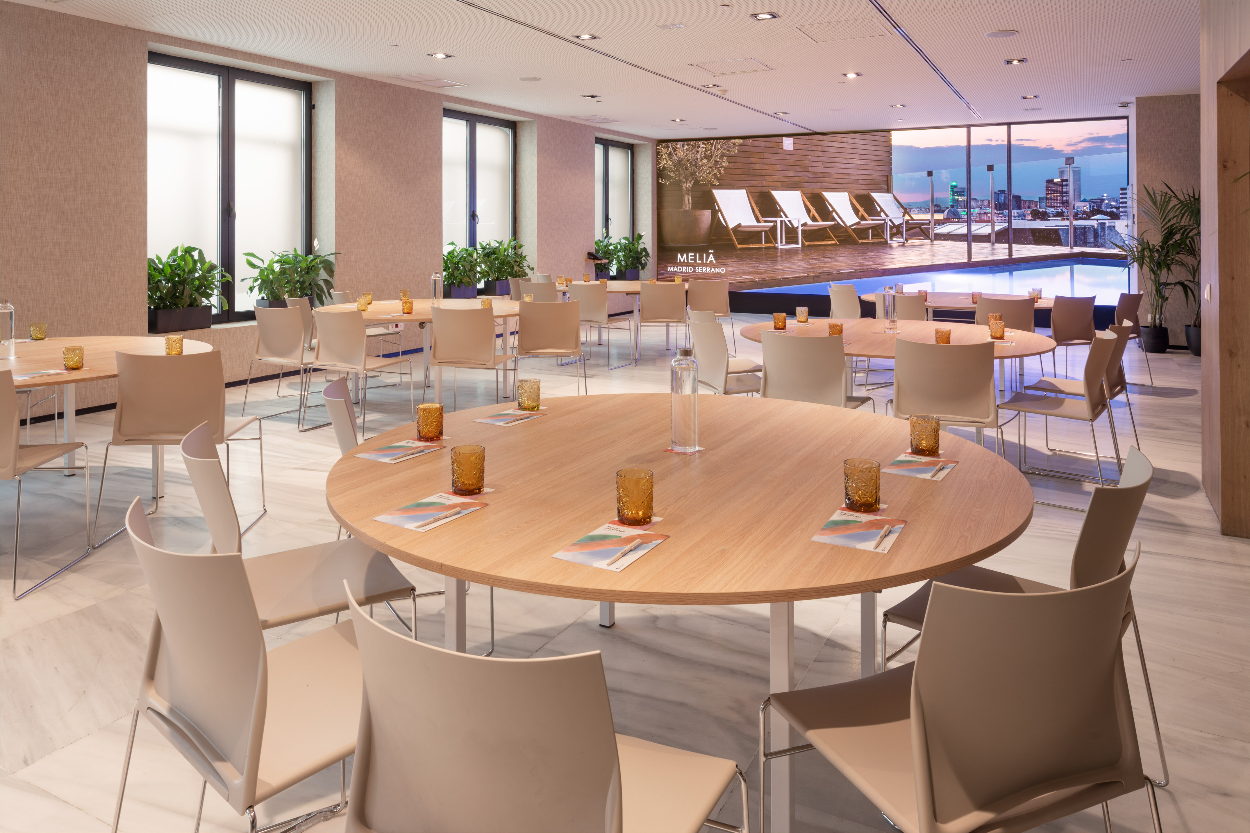 Meliá Madrid Serrano conference room with round tables, city view, and rooftop pool.