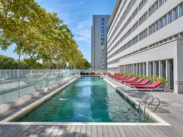 a pool with lounge chairs and a building