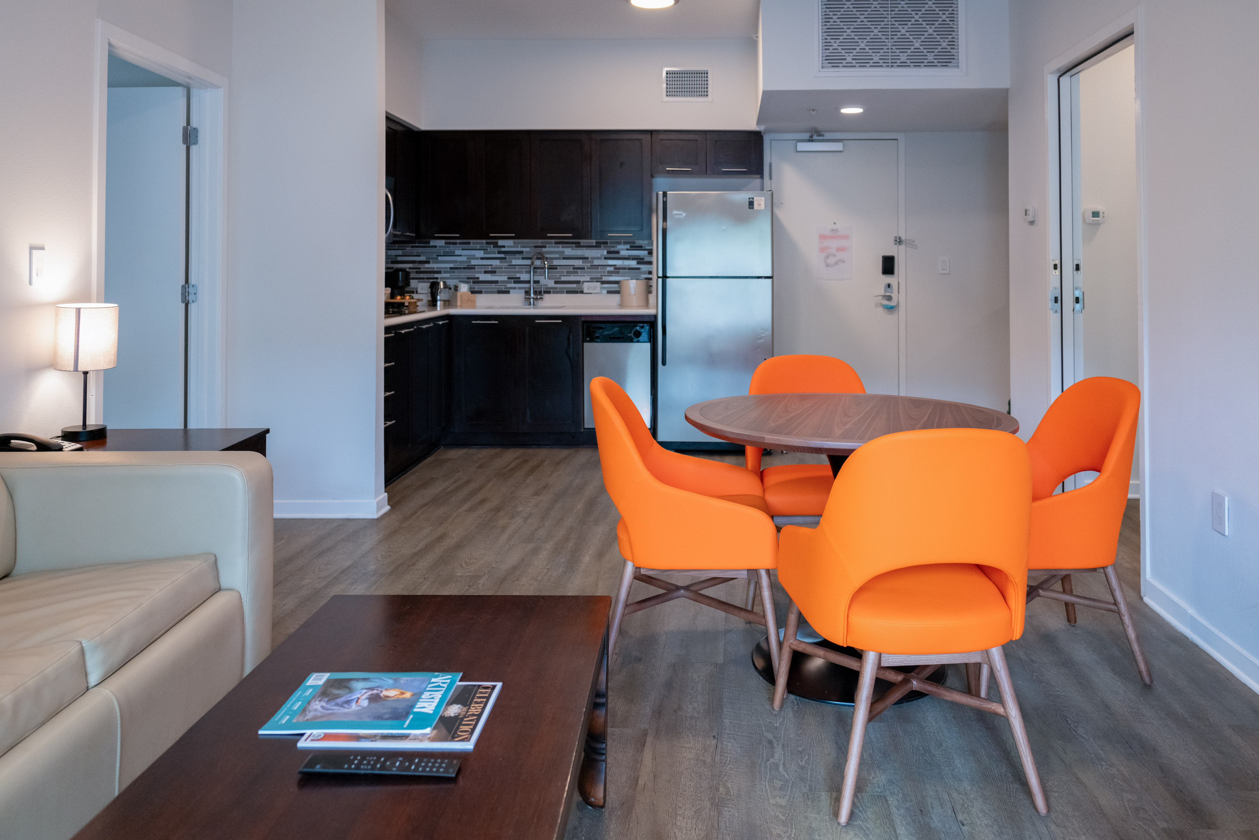 Open concept living, dining, and kitchen area with orange chairs.