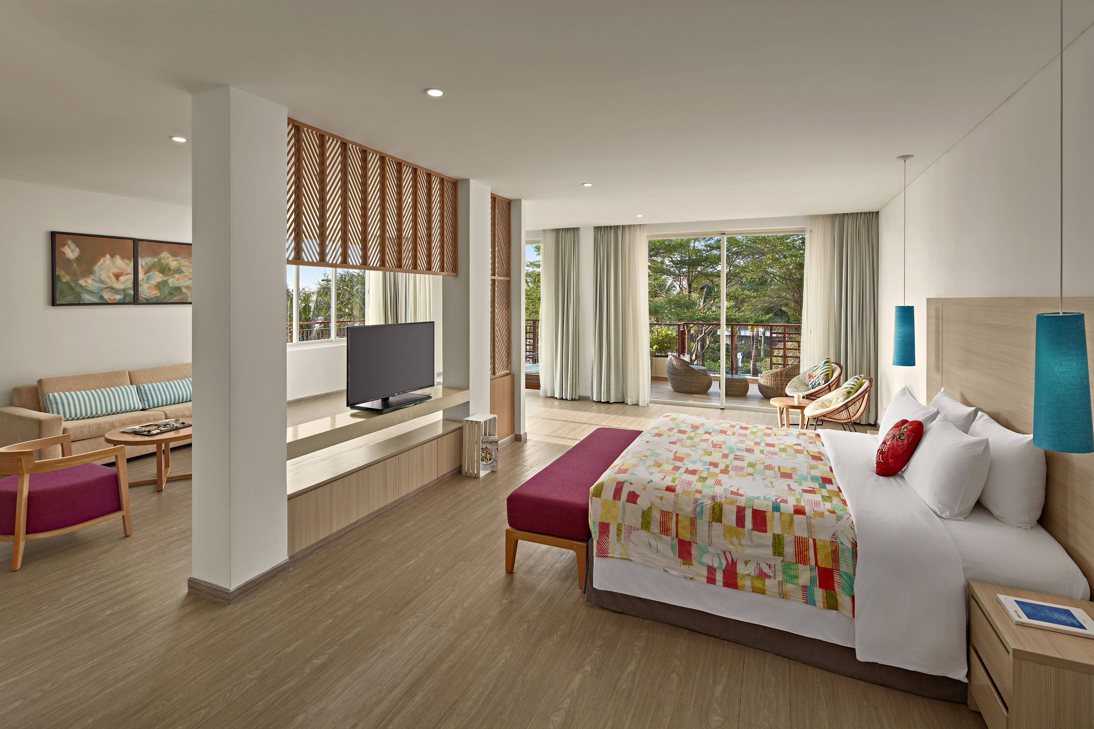 Modern hotel suite with bedroom, living area, balcony, and tropical view.