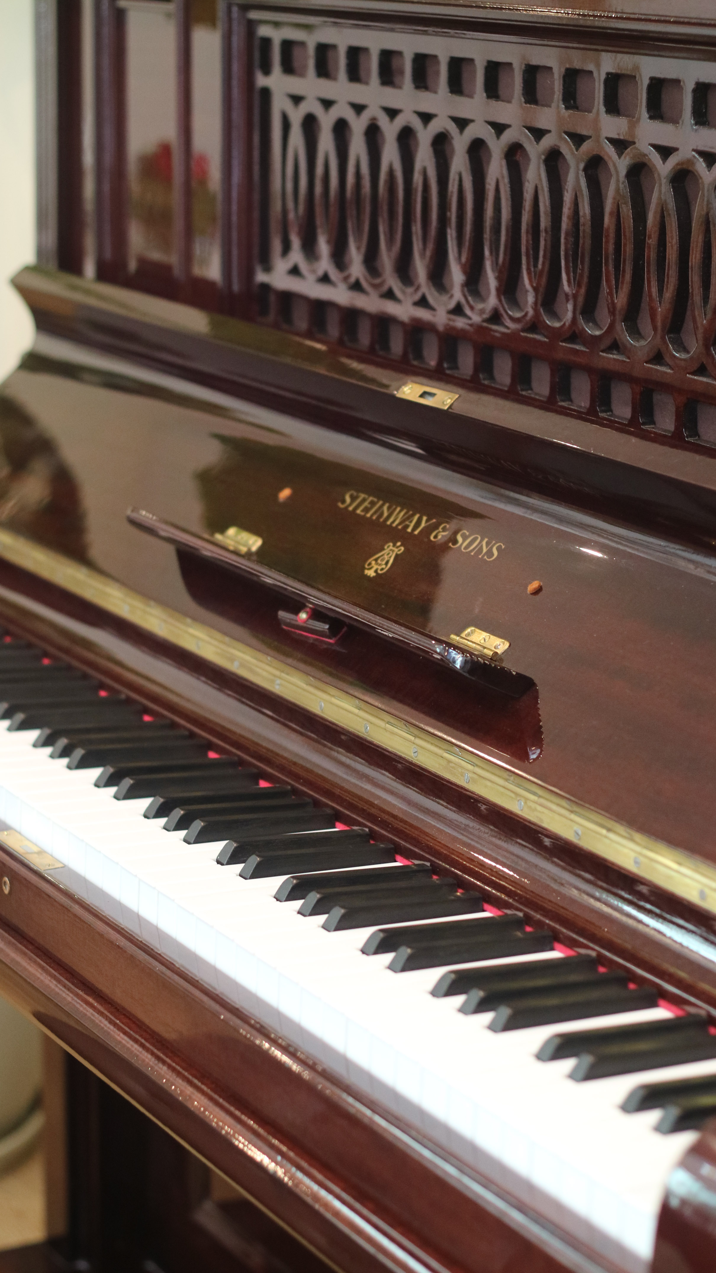 Steinway & Sons piano, dark wood finish, keys, and intricate top design.
