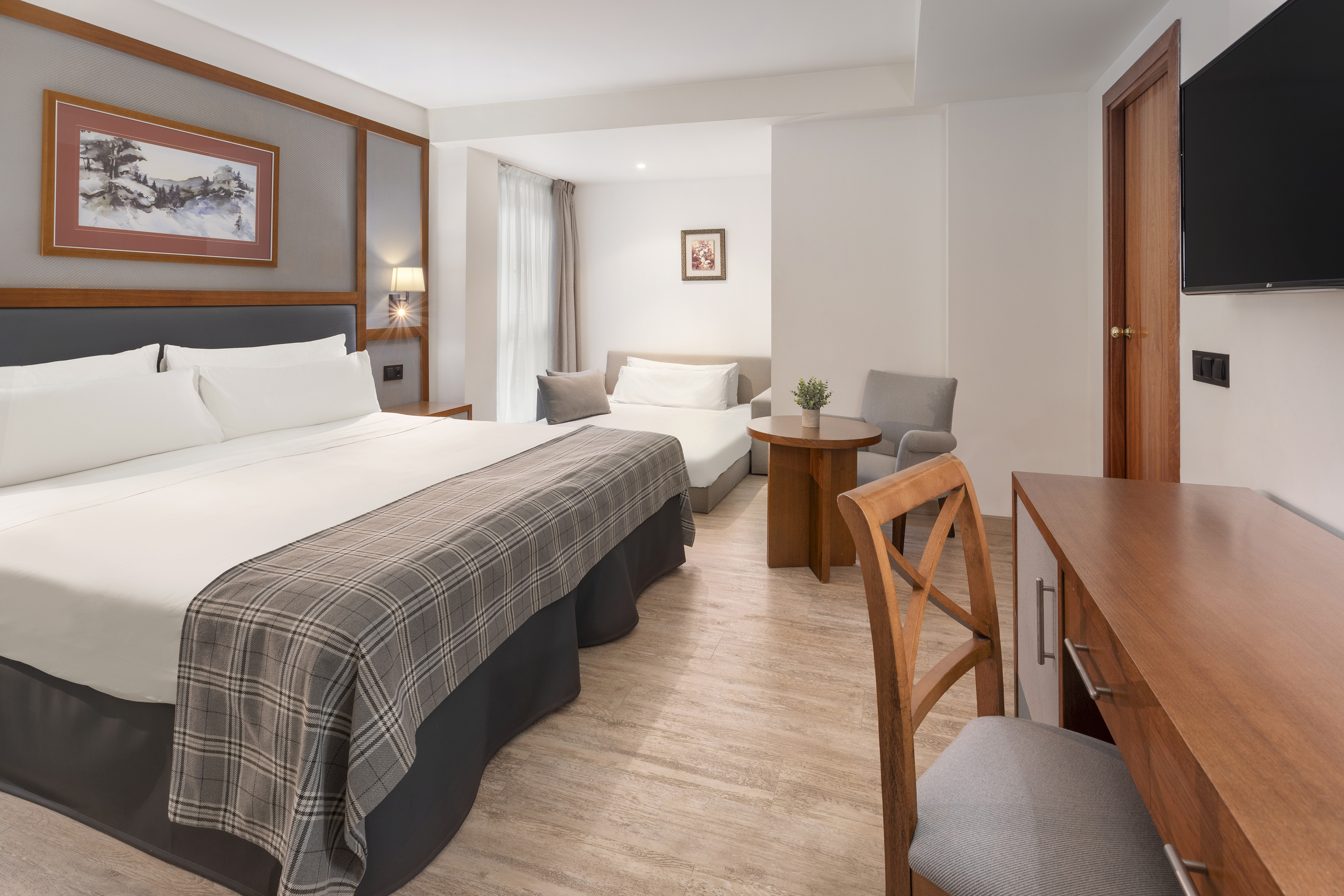 Spacious hotel room featuring a bed, sofa bed, work desk, and seating area.