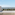 Balcony with glass railing overlooking bay, palm trees, and distant city skyline.