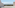 Balcony with glass railing overlooking bay, palm trees, and distant city skyline.