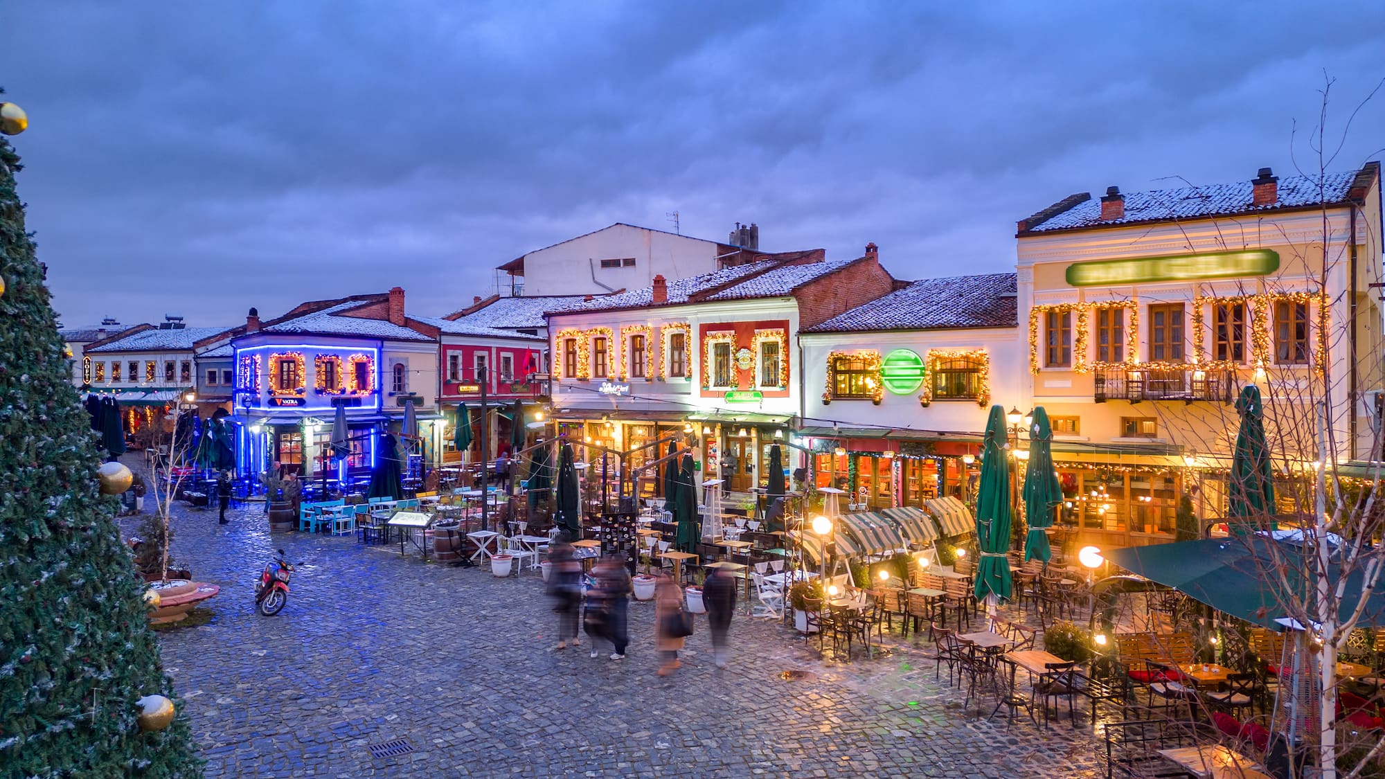 a street with tables and chairs and people in the street