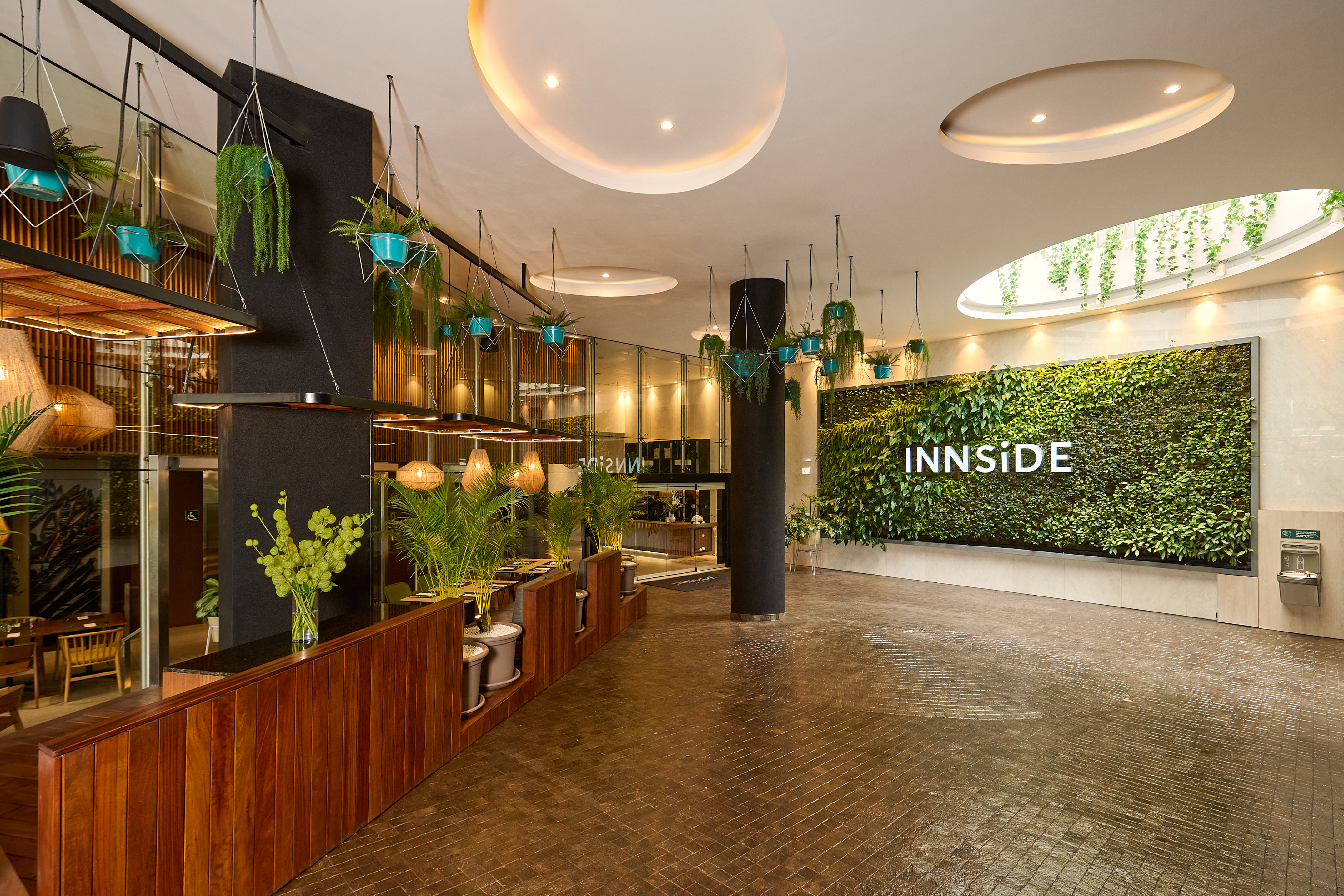 INNSiDE hotel lobby, green living wall, hanging plants, modern wood design.