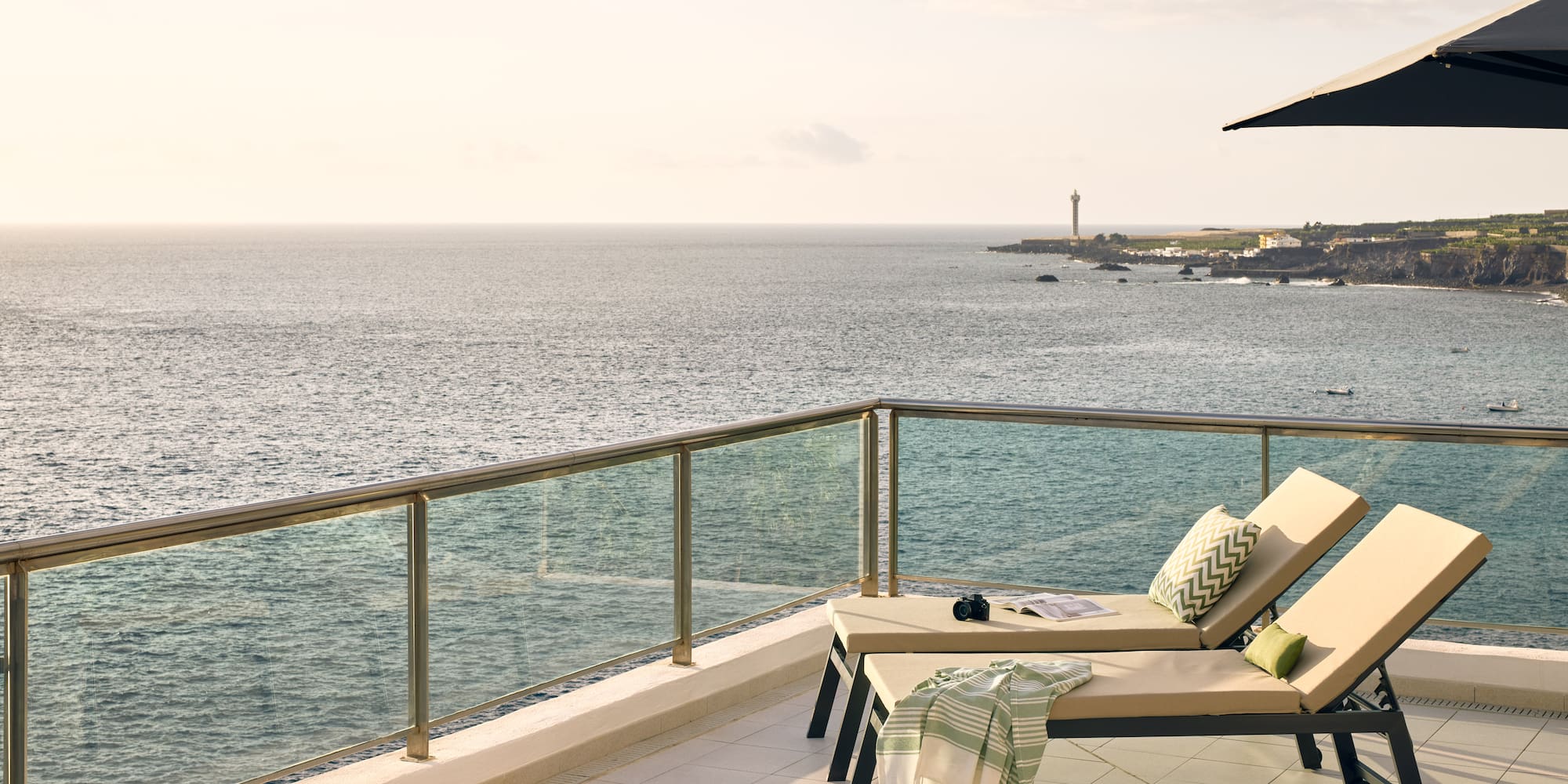 a deck with chairs and a railing overlooking the ocean