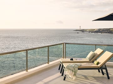 a deck with chairs and a railing overlooking the ocean