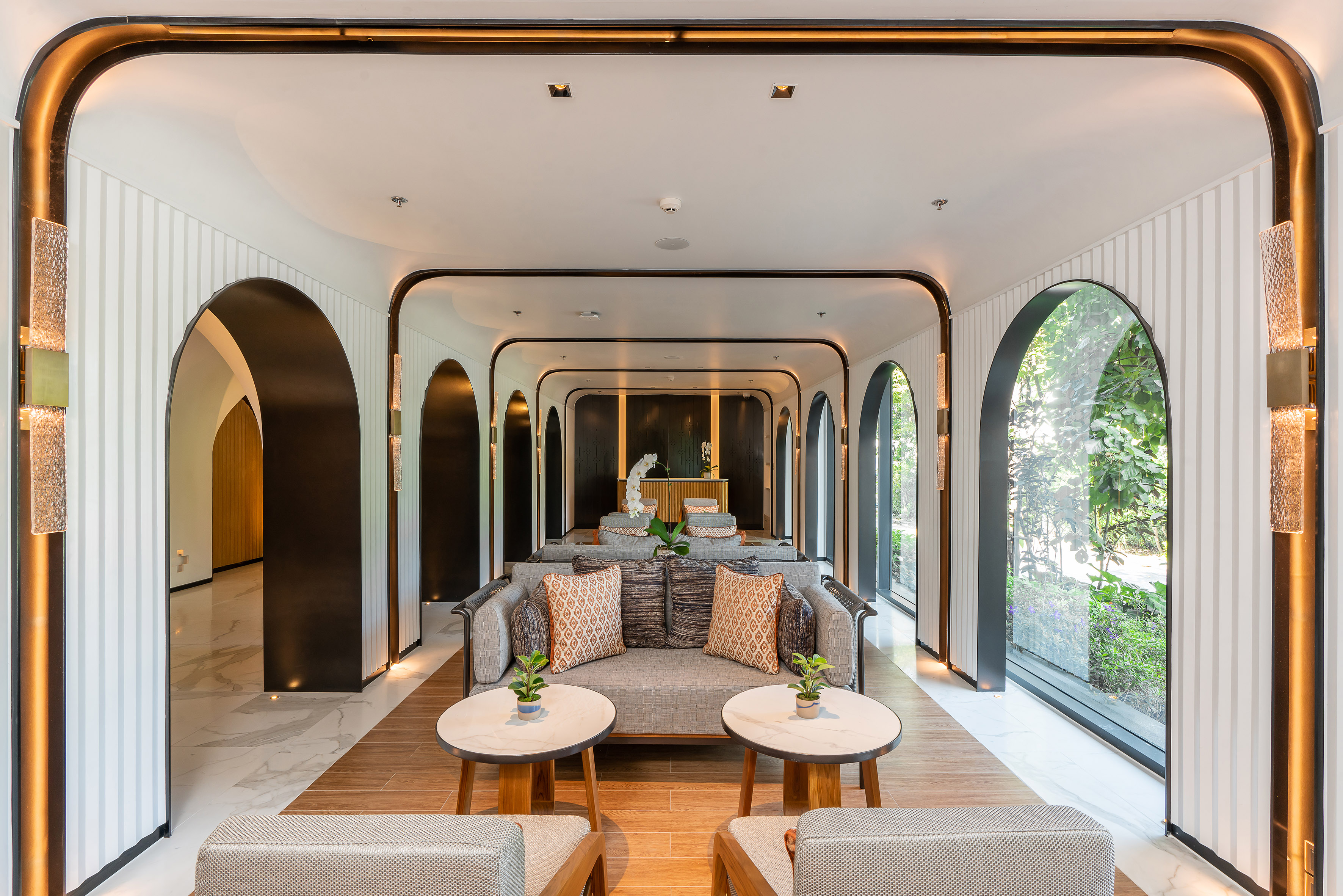Modern hotel lobby lounge with arched design, stylish sofas, and garden views.
