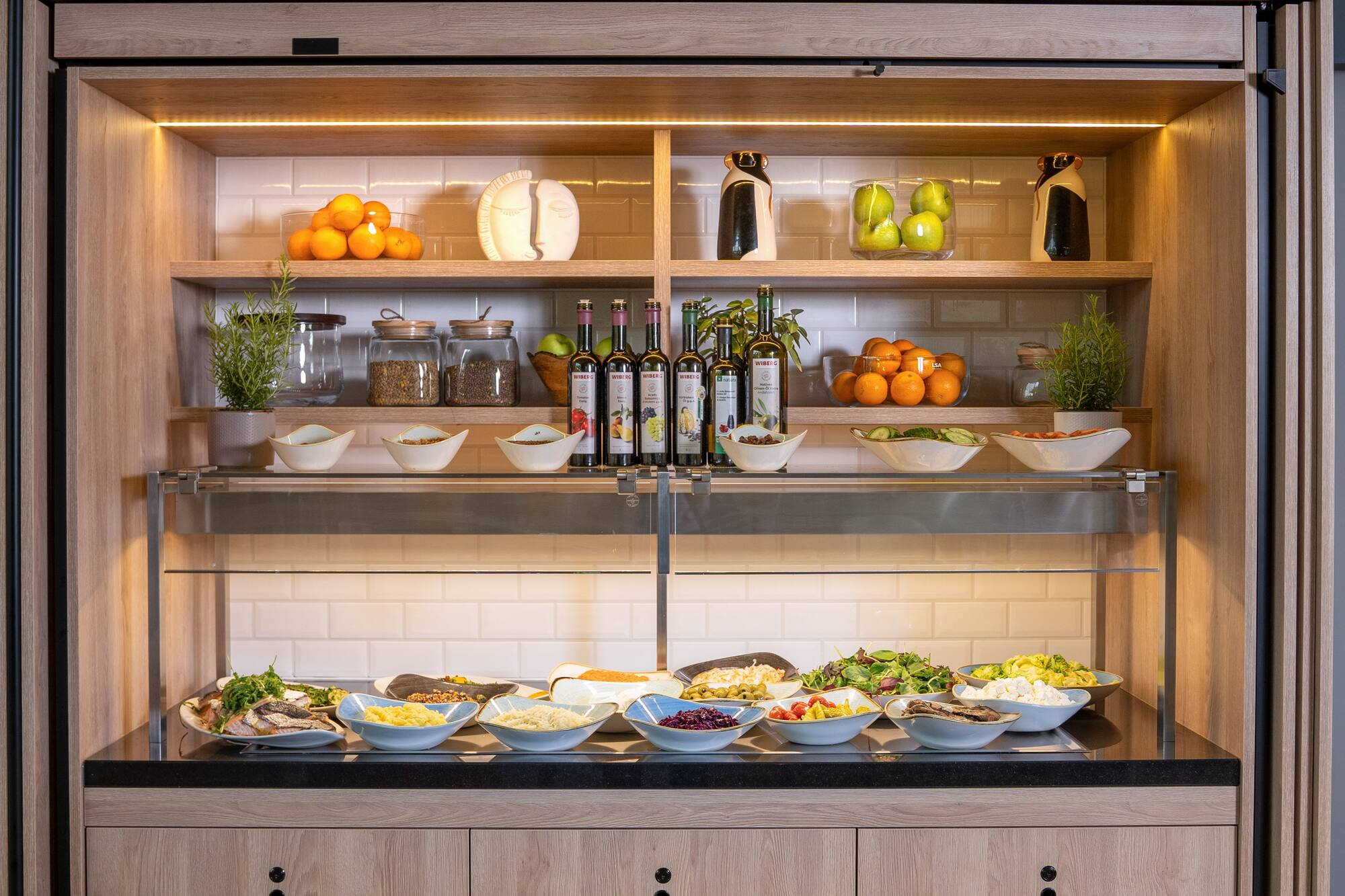 Modern buffet bar: fresh salads, fruits, oils, and various prepared dishes.