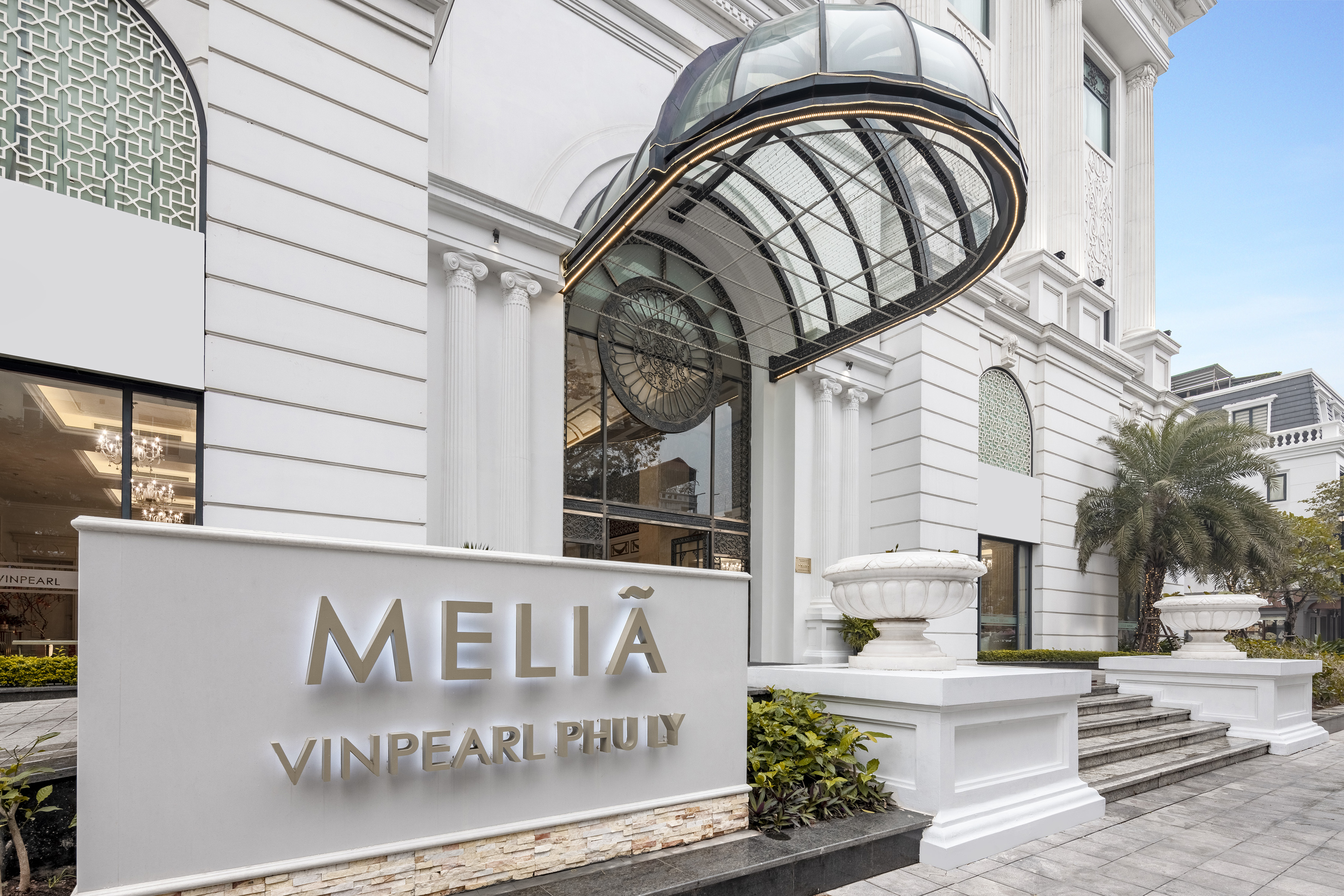 Melia Vinpearl Phu Ly hotel entrance with white facade and modern glass canopy.