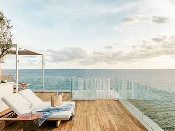 a deck with a chair and table overlooking the ocean
