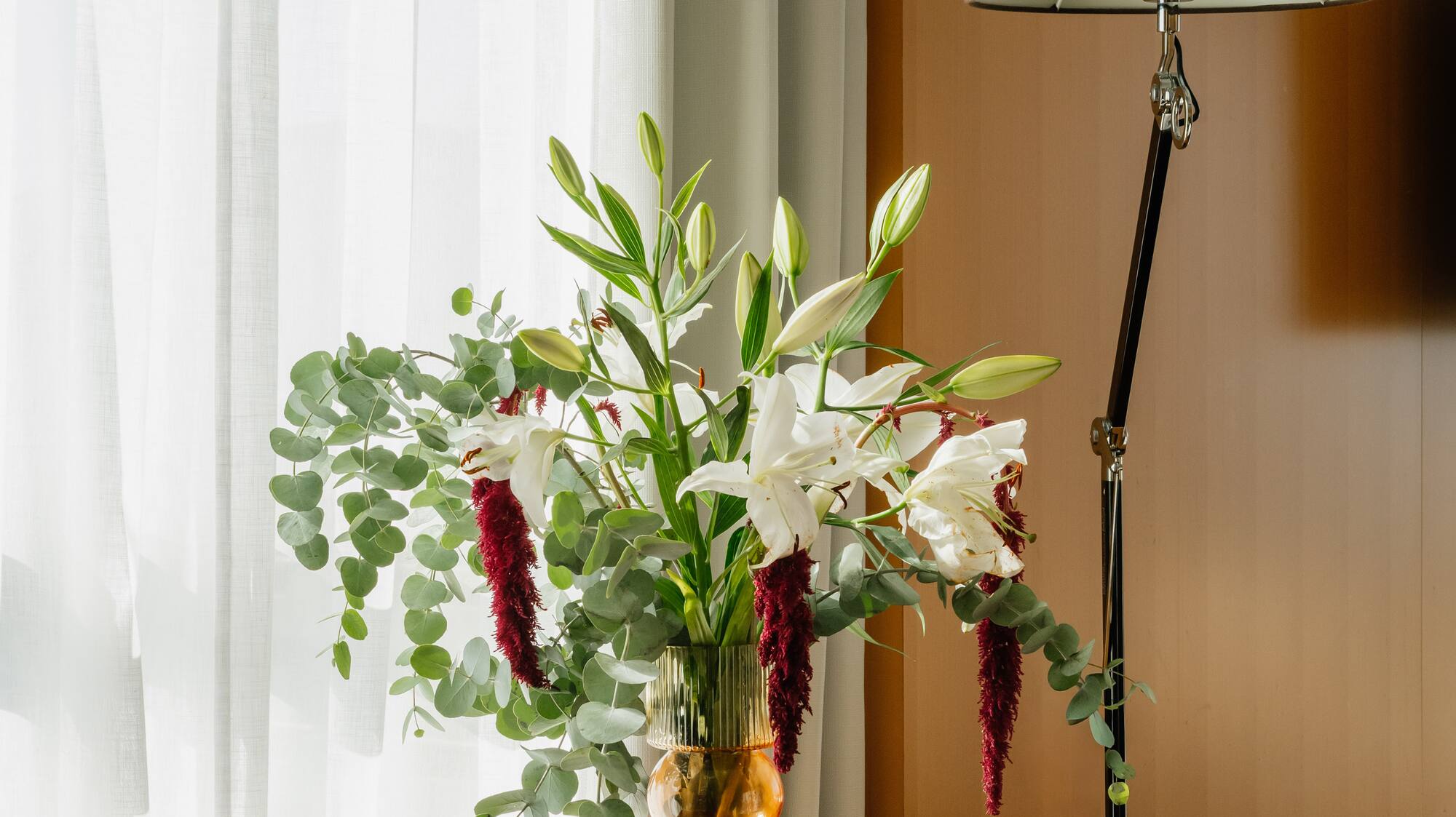 a vase of flowers and a lamp on a table