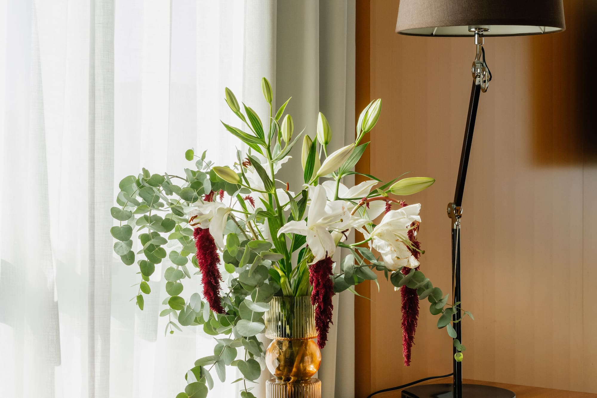 a vase of flowers and a lamp on a table