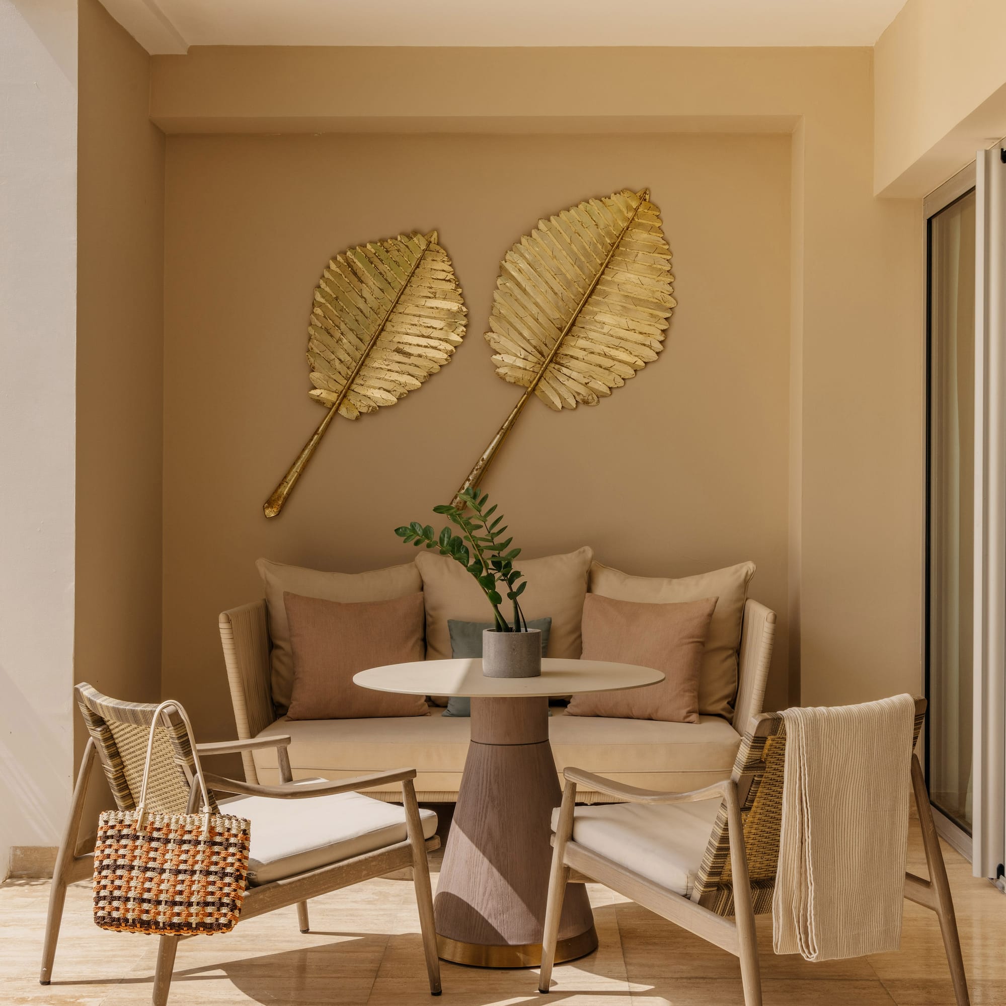 Luxury patio with outdoor seating, golden leaf wall decor, and tropical plants.