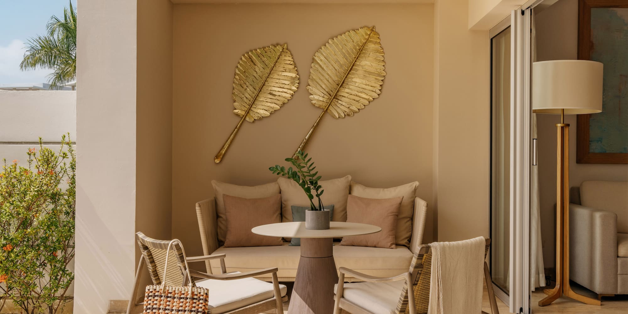 Luxury patio with outdoor seating, golden leaf wall decor, and tropical plants.