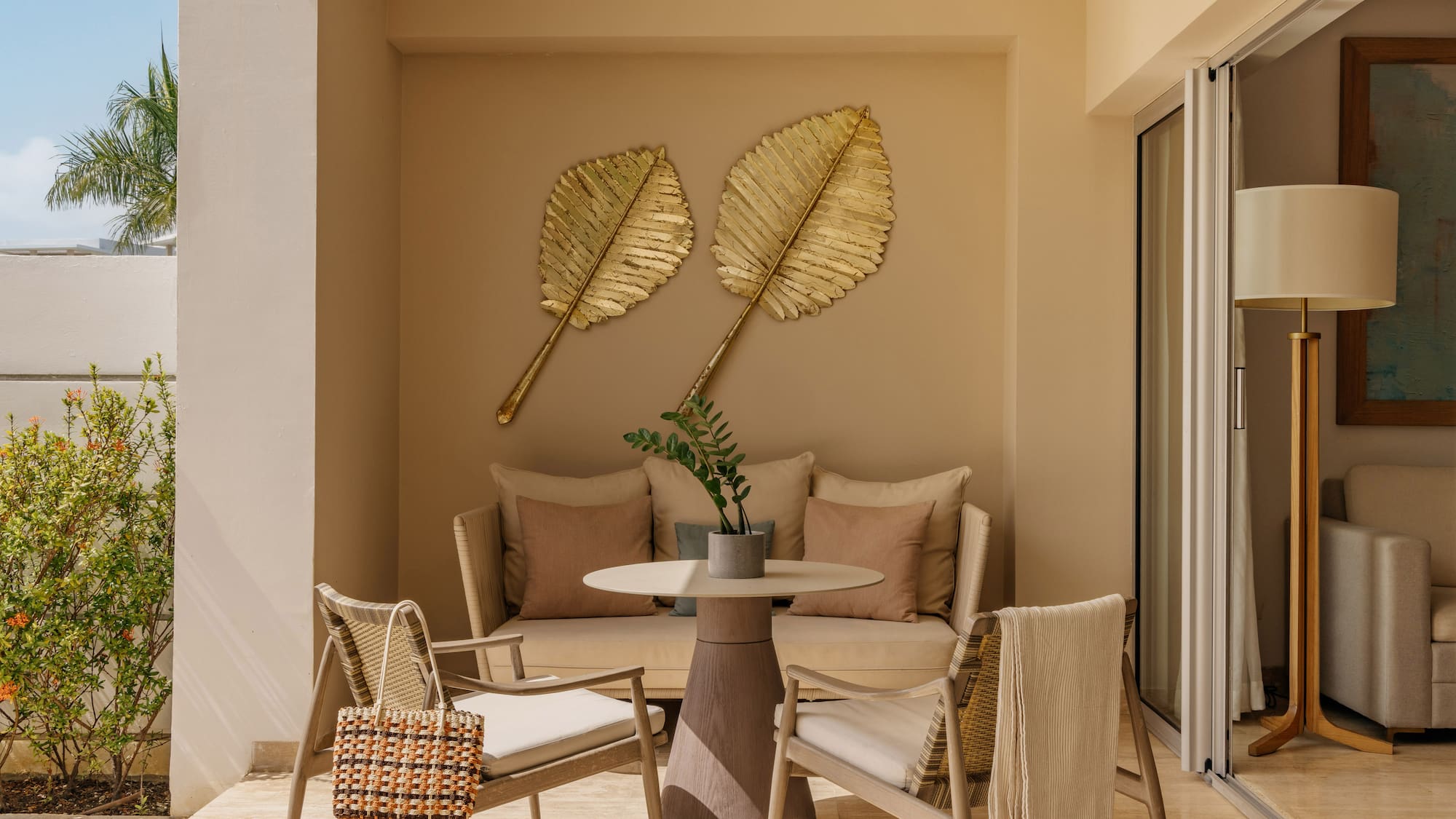 Luxury patio with outdoor seating, golden leaf wall decor, and tropical plants.
