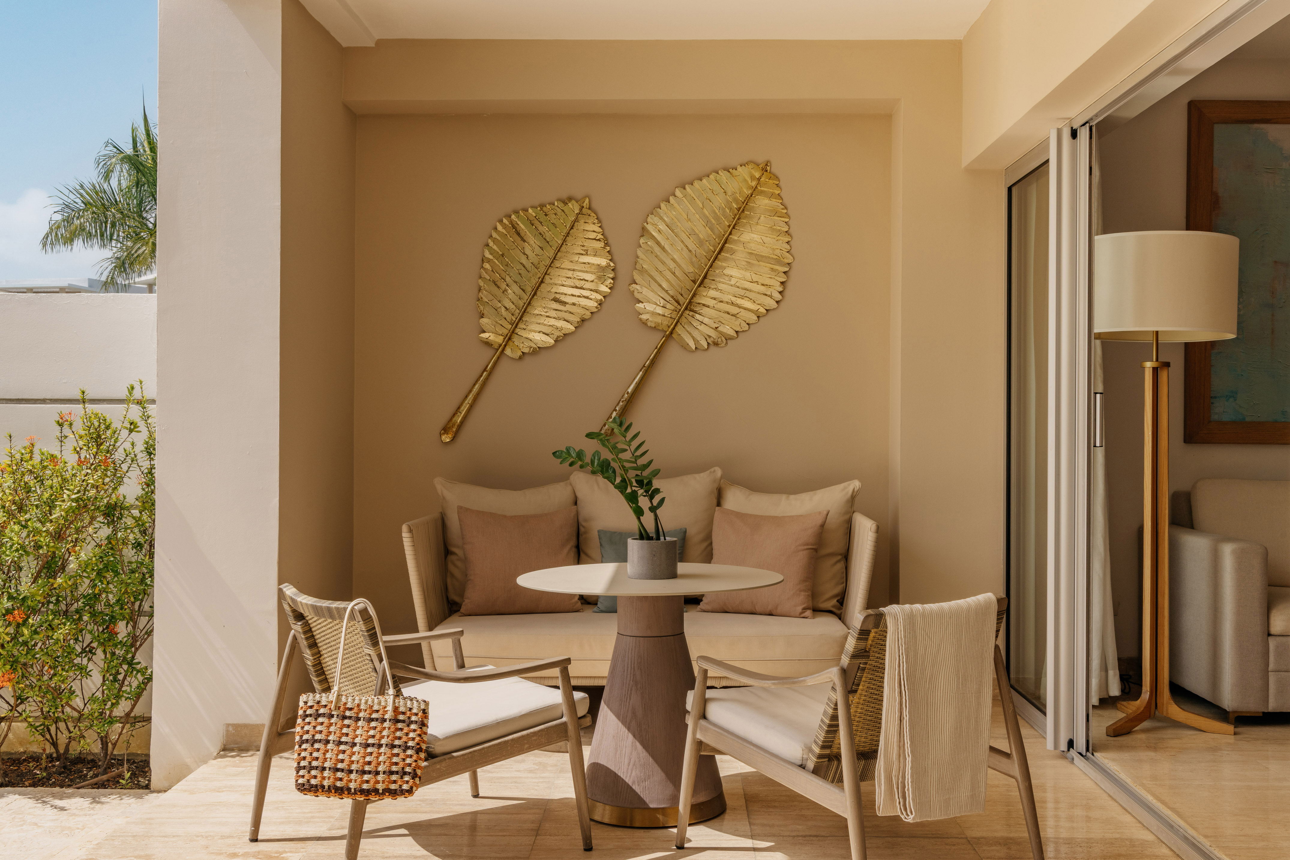 Luxury patio with outdoor seating, golden leaf wall decor, and tropical plants.