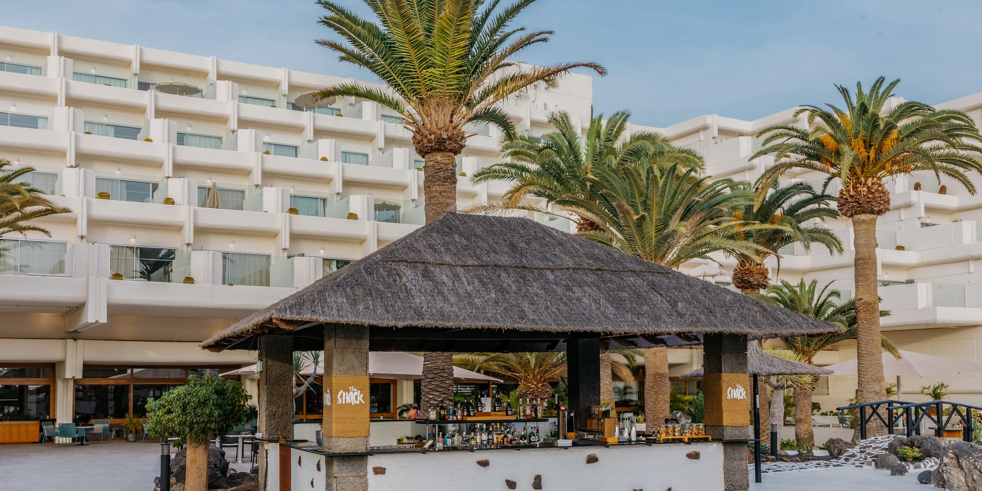 a bar with a straw roof and palm trees