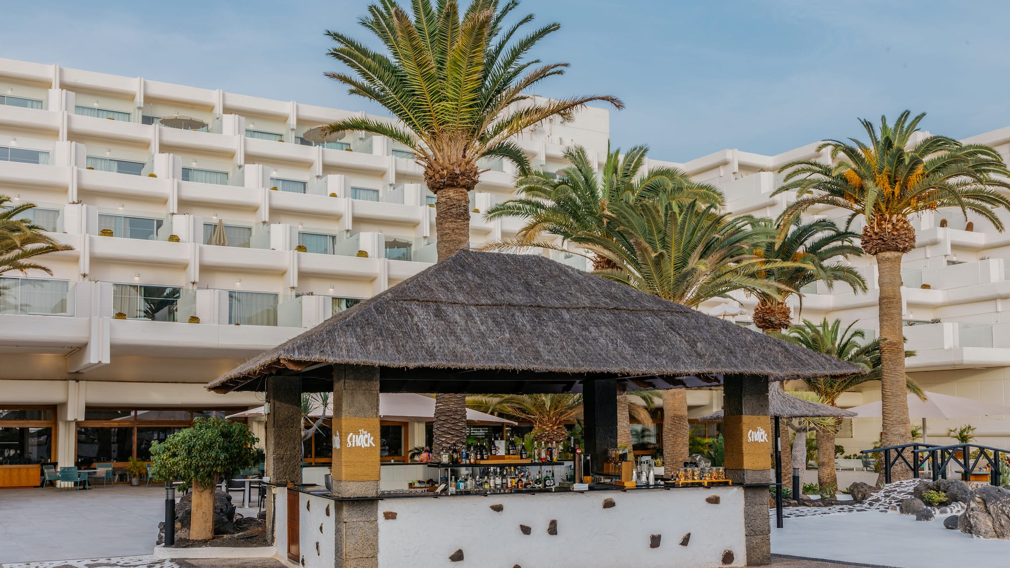 a bar with a straw roof and palm trees