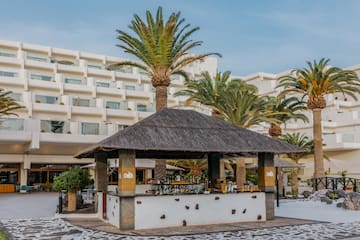 a bar with a straw roof and palm trees