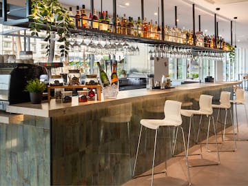 a bar with wine glasses and bottles on top