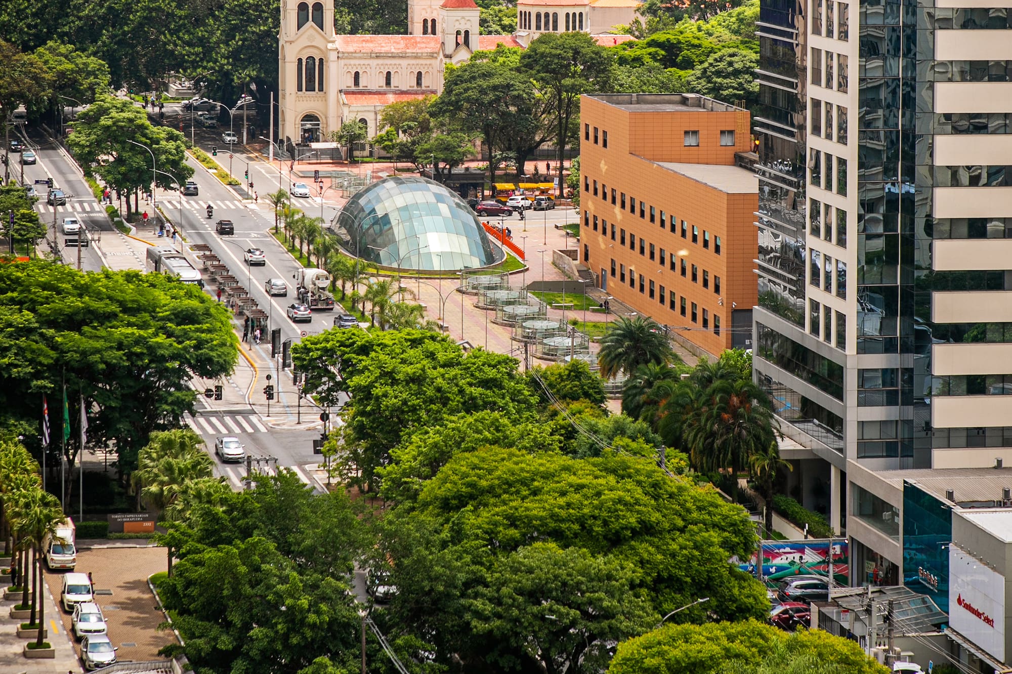 Busy city street with church, modern dome, traffic, trees, and tall buildings.