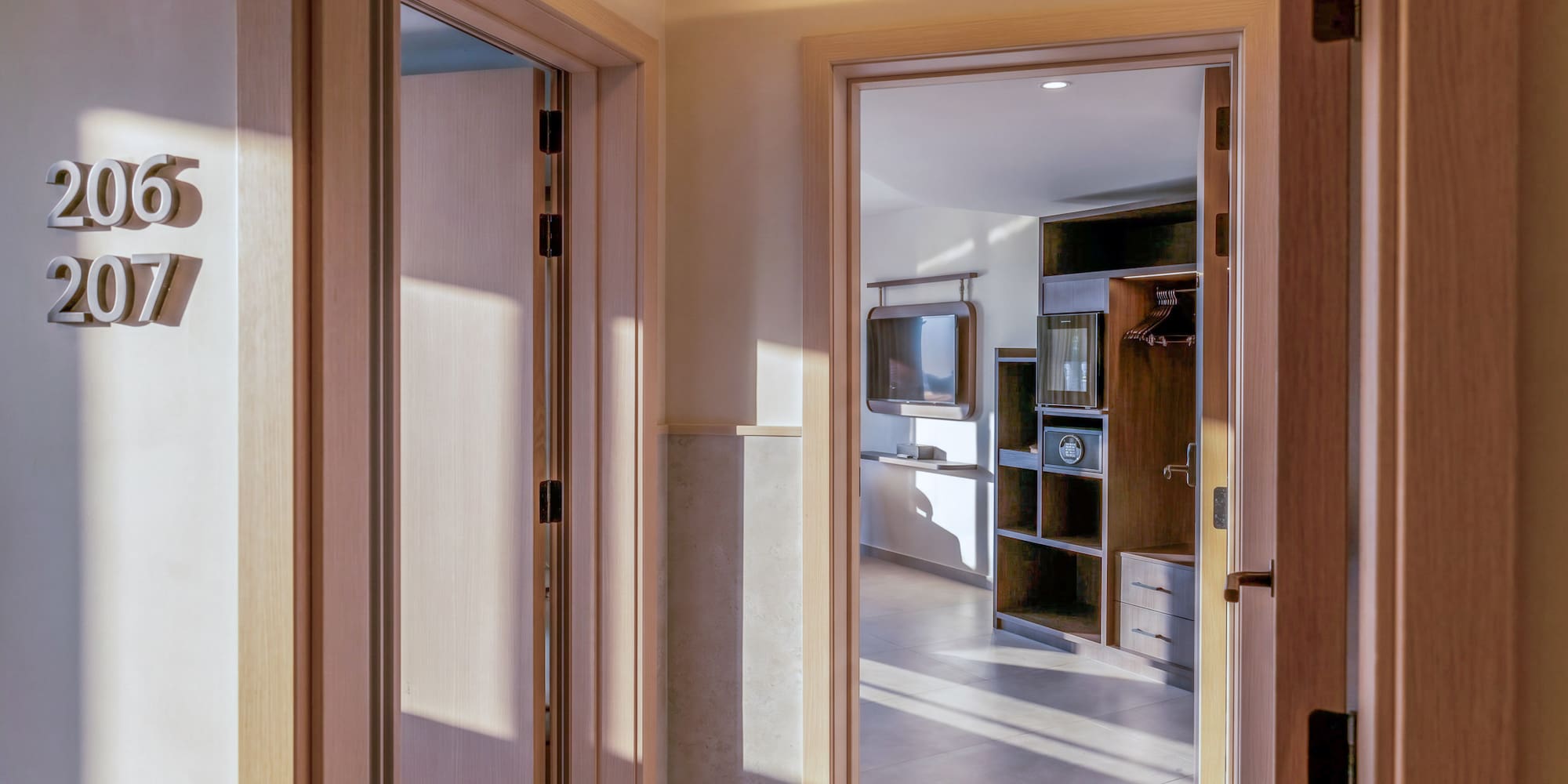 Hotel hallway, room numbers 206, 207, leading to a modern guest room.