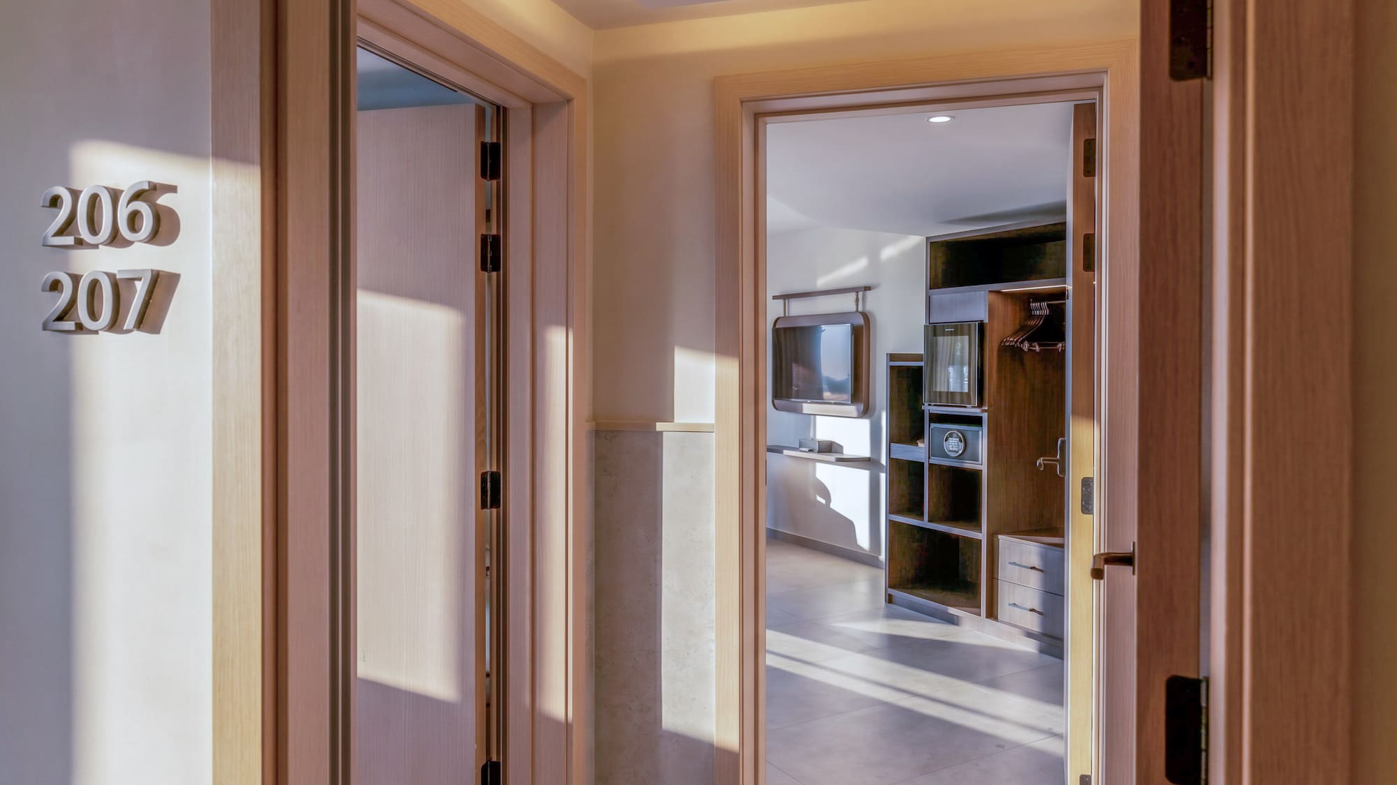 Open hotel room doors 206, 207 revealing a bright, modern interior with TV and safe.