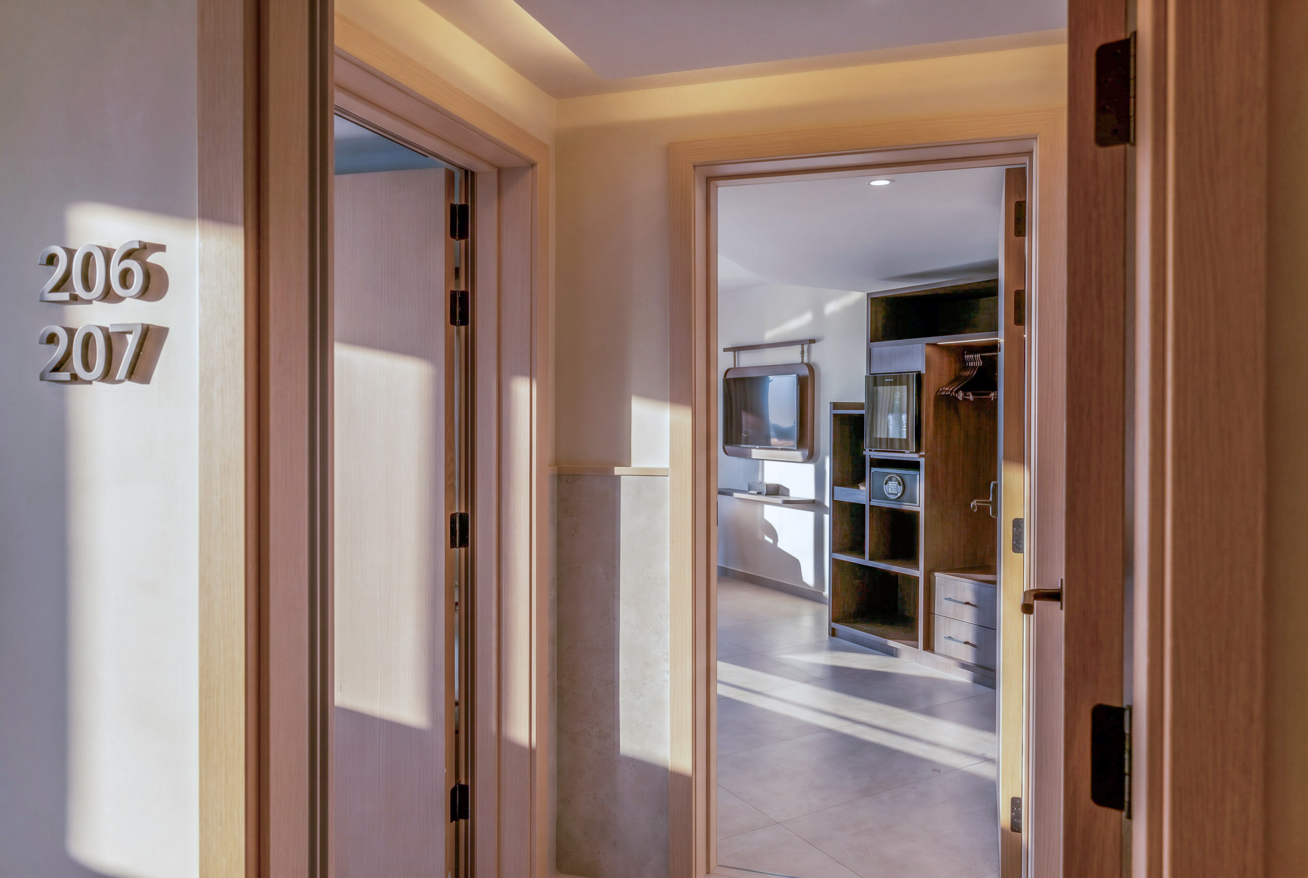 Hotel hallway, room numbers 206, 207, leading to a modern guest room.