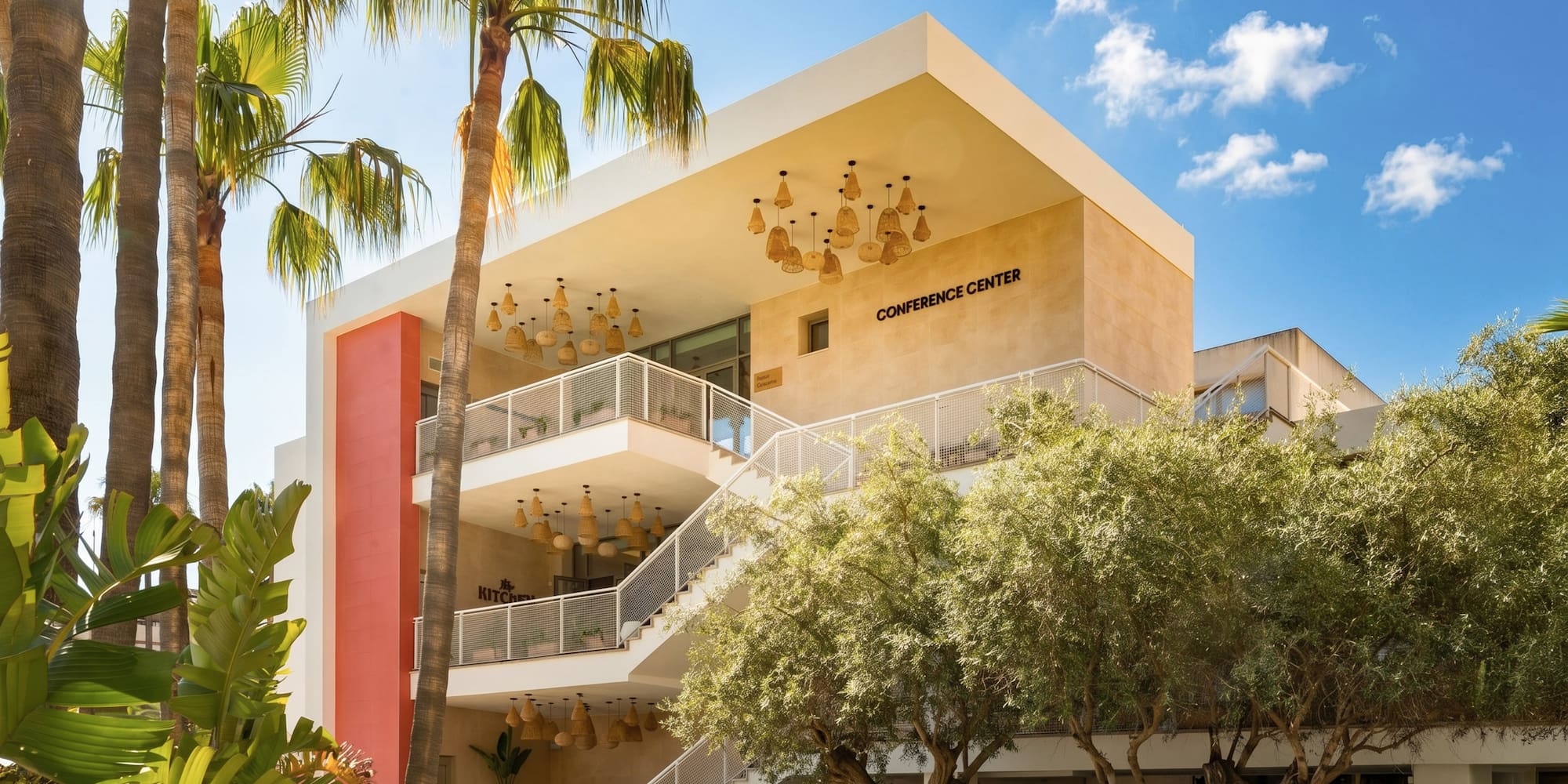 Modern conference center exterior with palm trees and stylish outdoor stairs.
