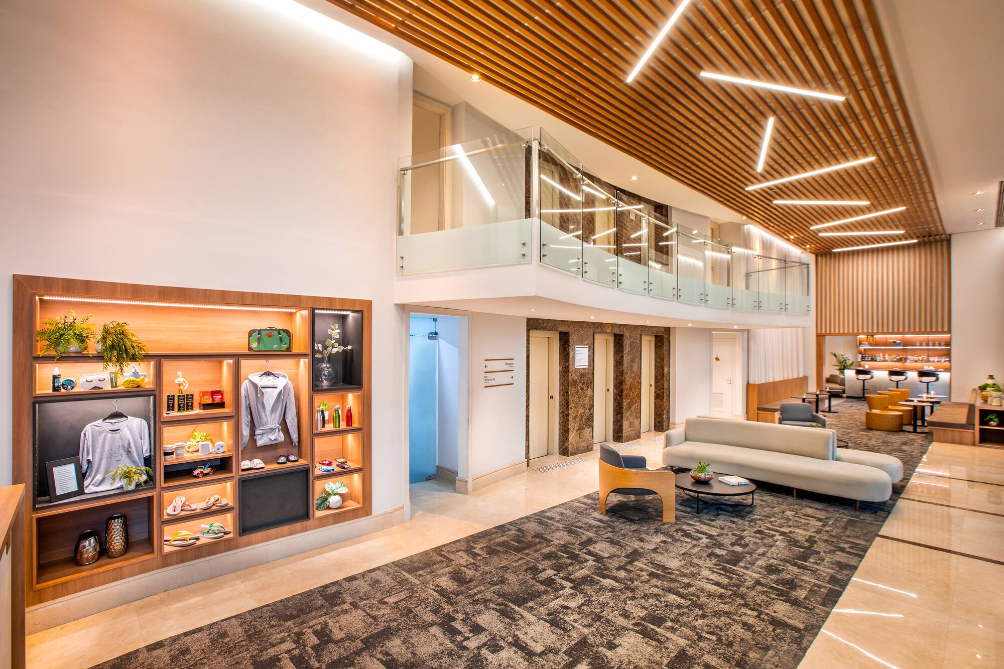 Modern hotel lobby with lounge seating, wood slat ceiling, and illuminated display.