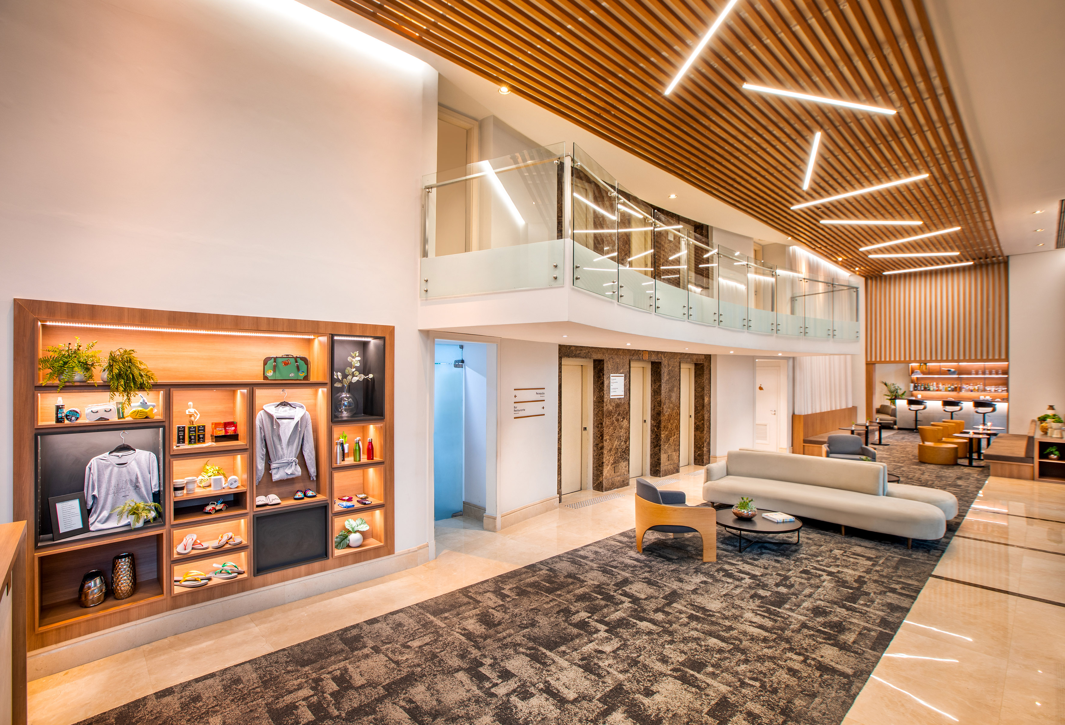 Modern hotel lobby with lounge seating, wood slat ceiling, and illuminated display.